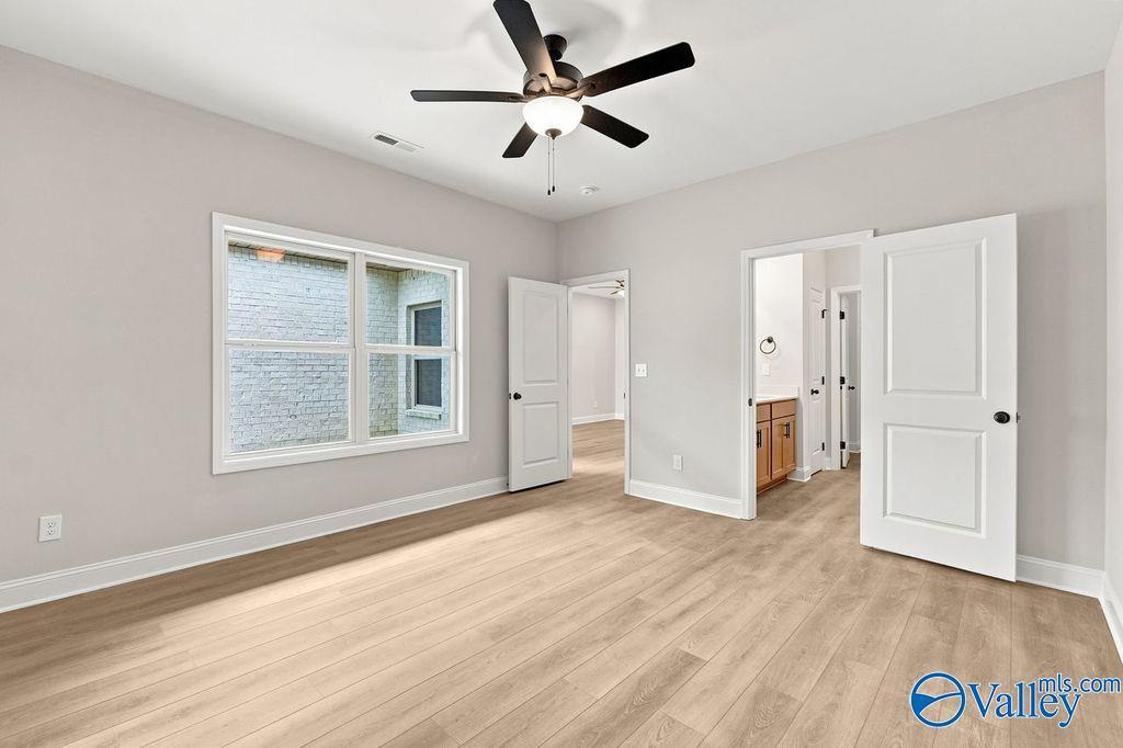Bright bedroom with wood-look flooring and en-suite bathroom in The Camilla C floor plan at The Retreat at Cain Park.