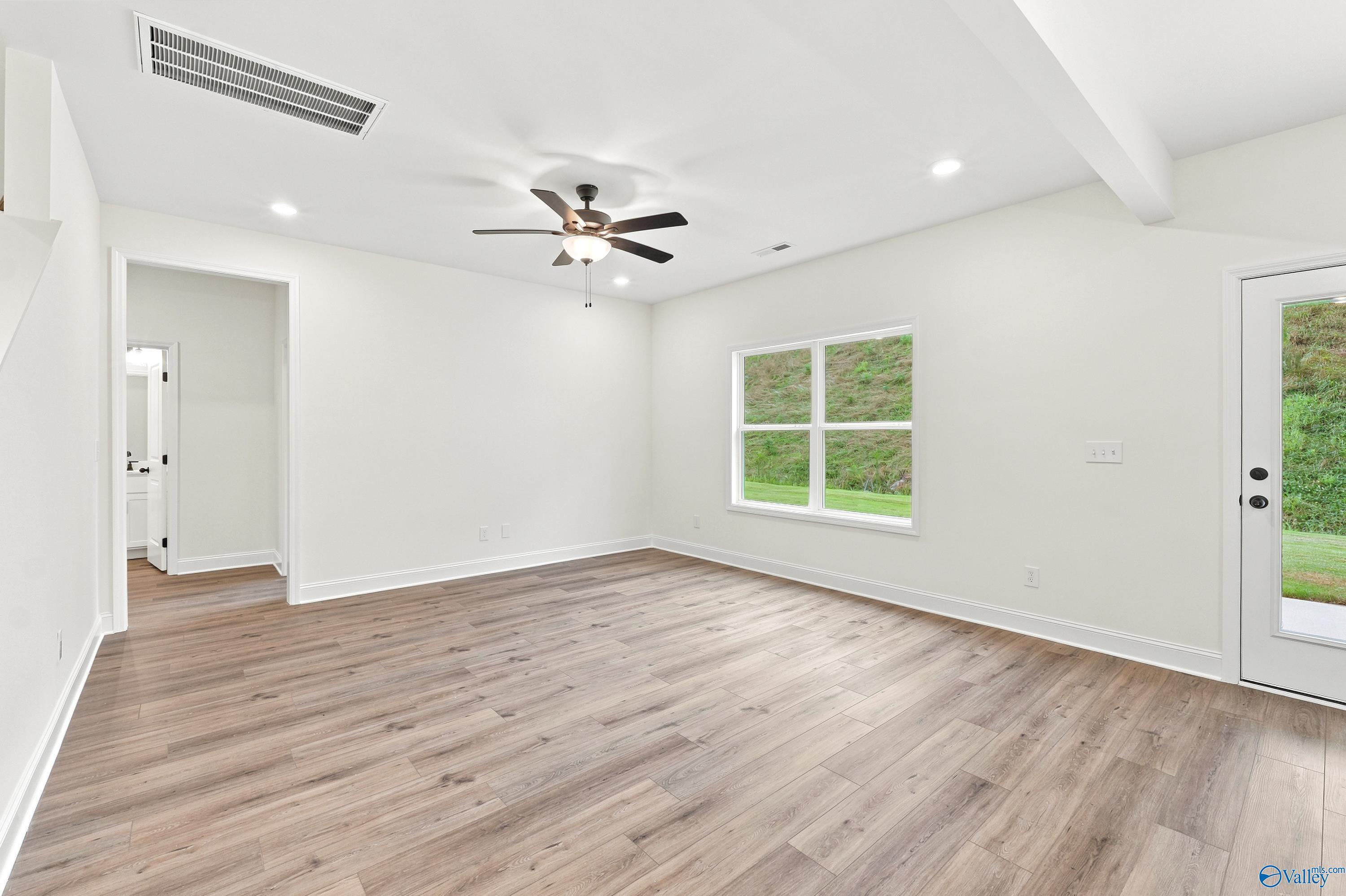 Bright living room with wood-look flooring and ceiling fan in The Shelby D floor plan at Noble Ridge, Cullman, Alabama.
