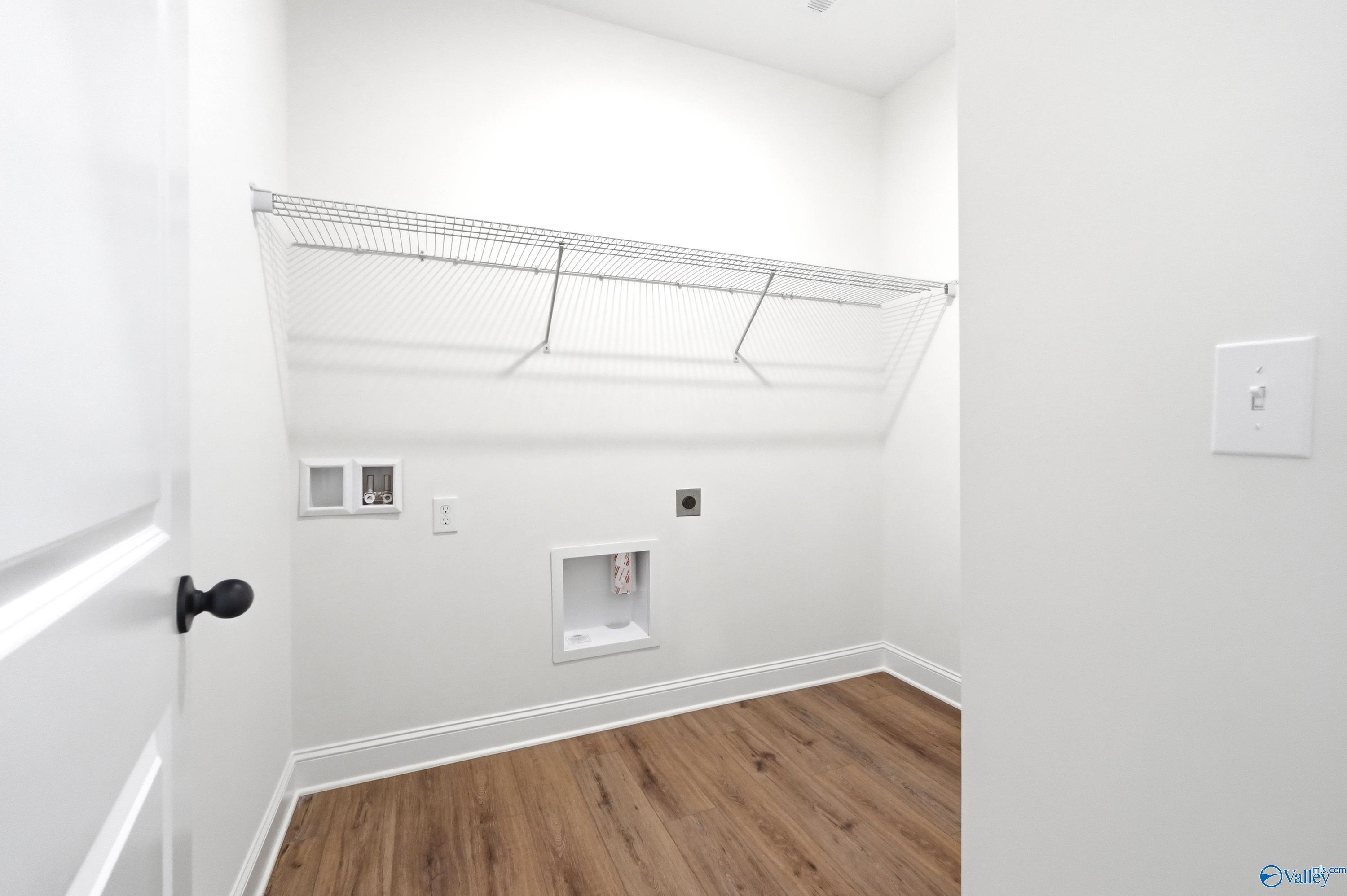 Laundry room with wire shelving and wood-look flooring in The Daphne C floor plan by Davidson Homes in Toney, Alabama.