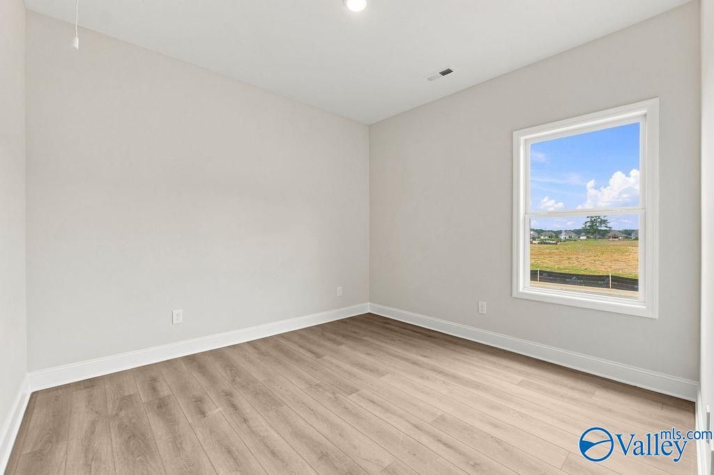 Bright bedroom with wood-look flooring in The Camilla B floor plan at The Retreat at Cain Park in Hartselle, Alabama.