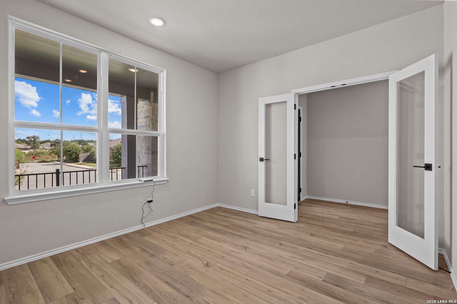 Bright flexible room with wood-look flooring, French glass doors, and large windows in Davidson Homes The Sequoia C, Royal Crest San Antonio