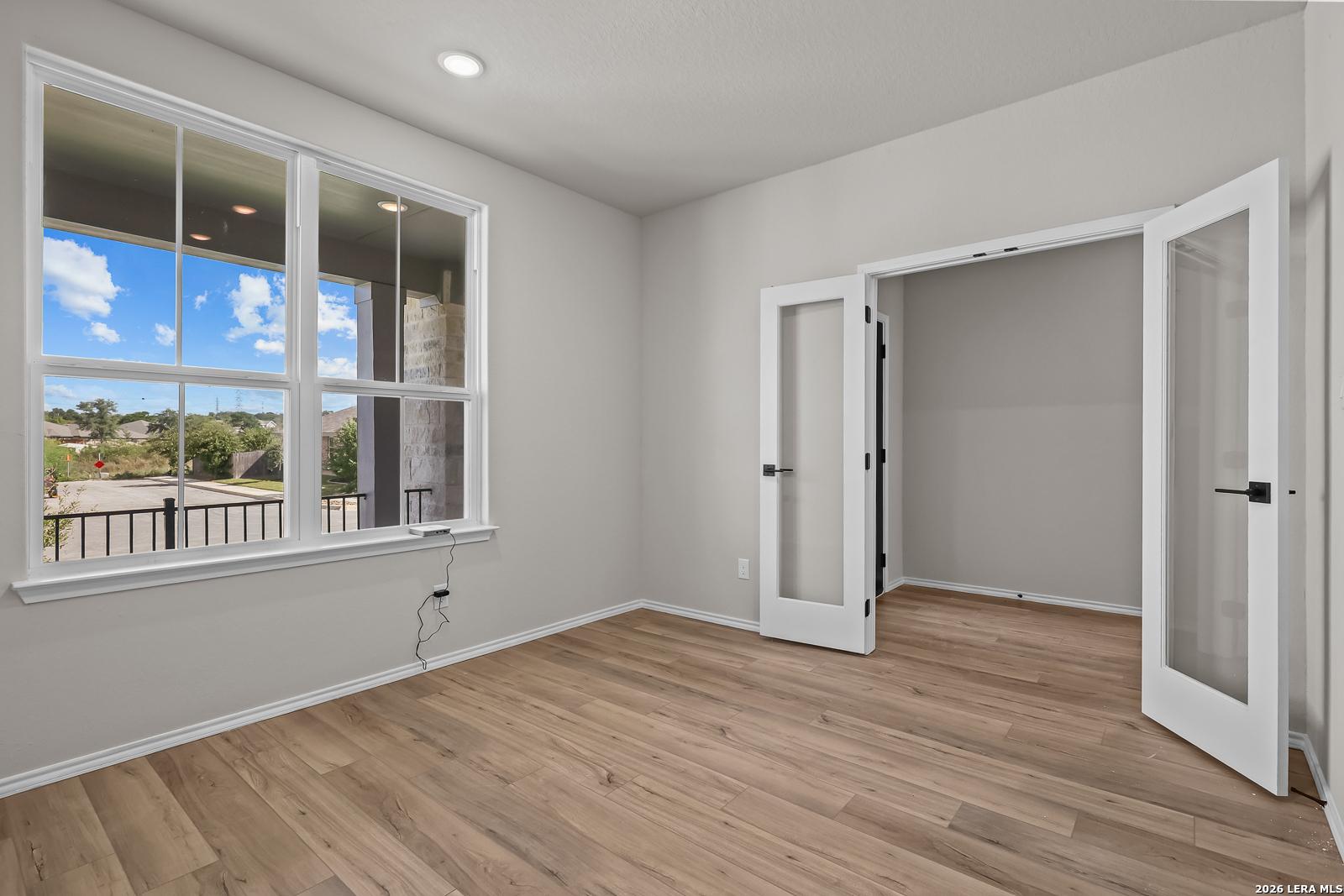 Bright flexible room with wood-look flooring, French glass doors, and large windows in Davidson Homes The Sequoia C, Royal Crest San Antonio