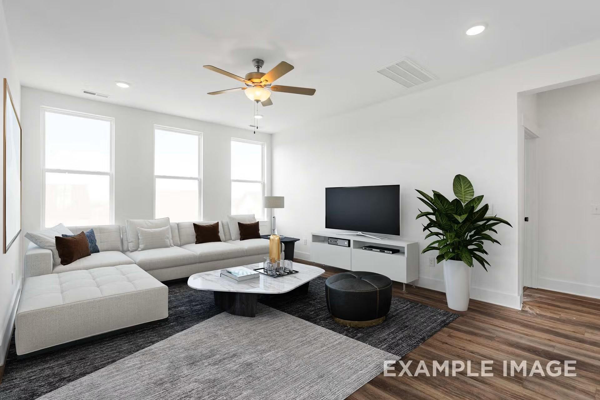 Modern living room with L-shaped white sofa, marble coffee table, TV console, and large windows in The Ash M floor plan, Davidson Homes, Royse City, Texas