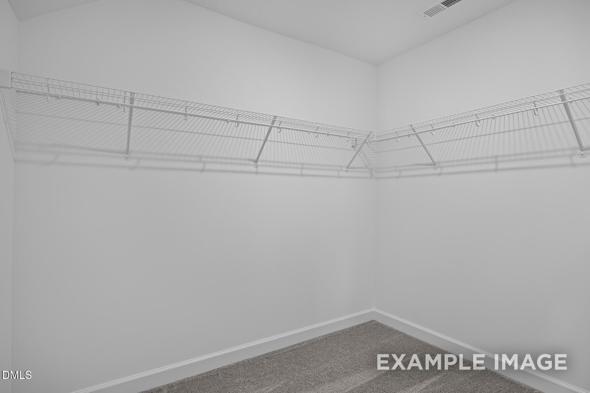 Spacious walk-in closet with wire shelving and hanging rods in The Cypress B II by Davidson Homes, Angier, NC