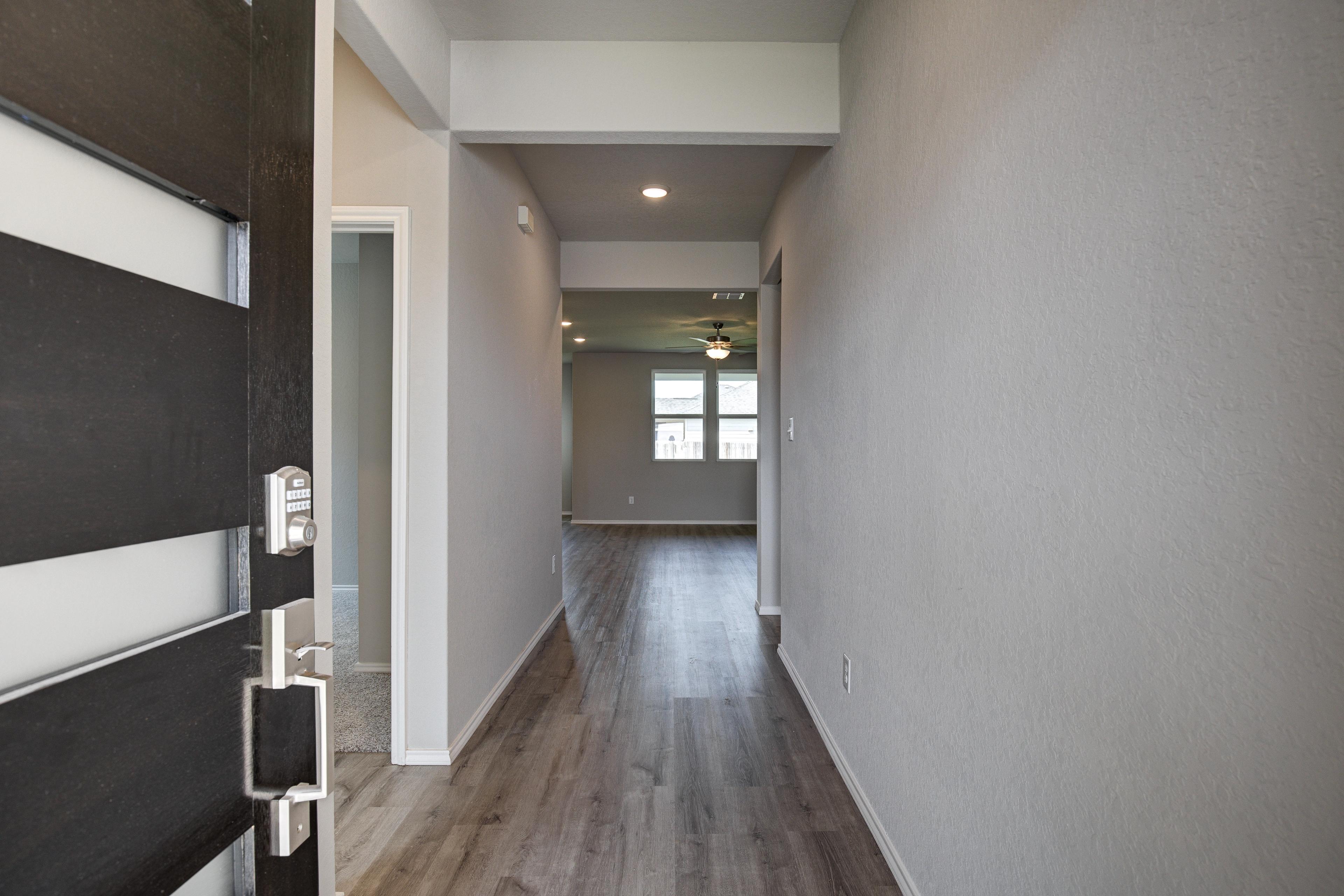 Spacious entry hallway in The Asheville home design with modern black door, hardwood floors, and recessed lighting