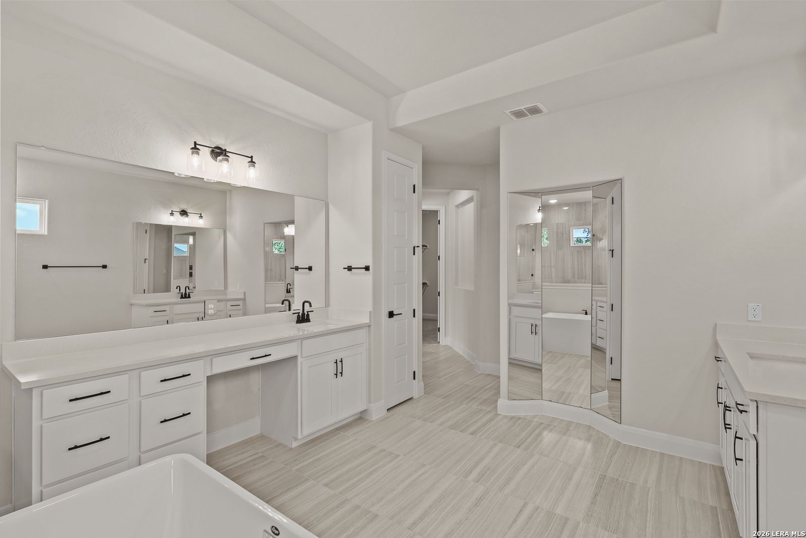 Modern primary bathroom with dual vanities and soaking tub in The Summerlin B floor plan by Davidson Homes in Castroville.