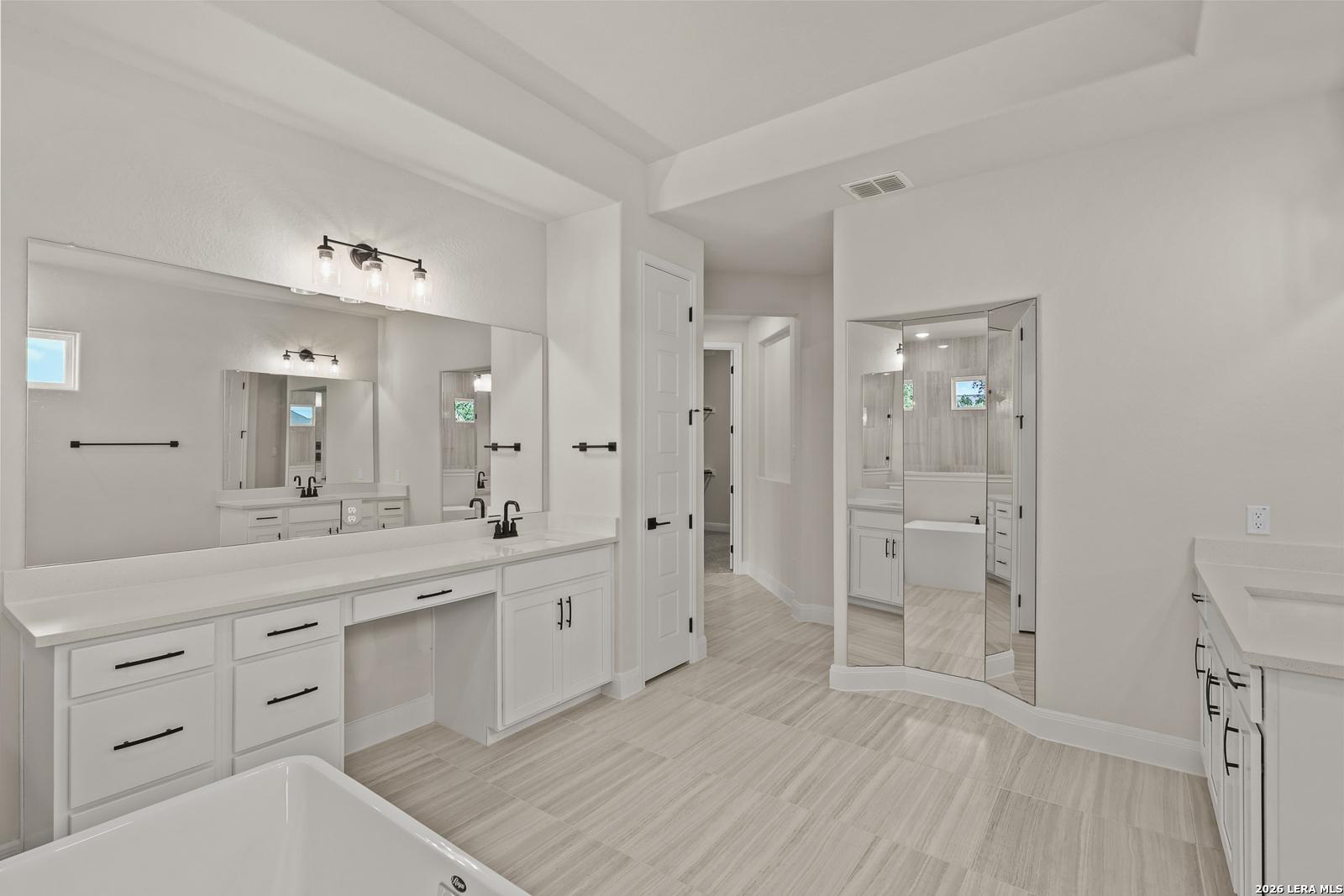 Modern primary bathroom with dual vanities and soaking tub in The Summerlin B floor plan by Davidson Homes in Castroville.