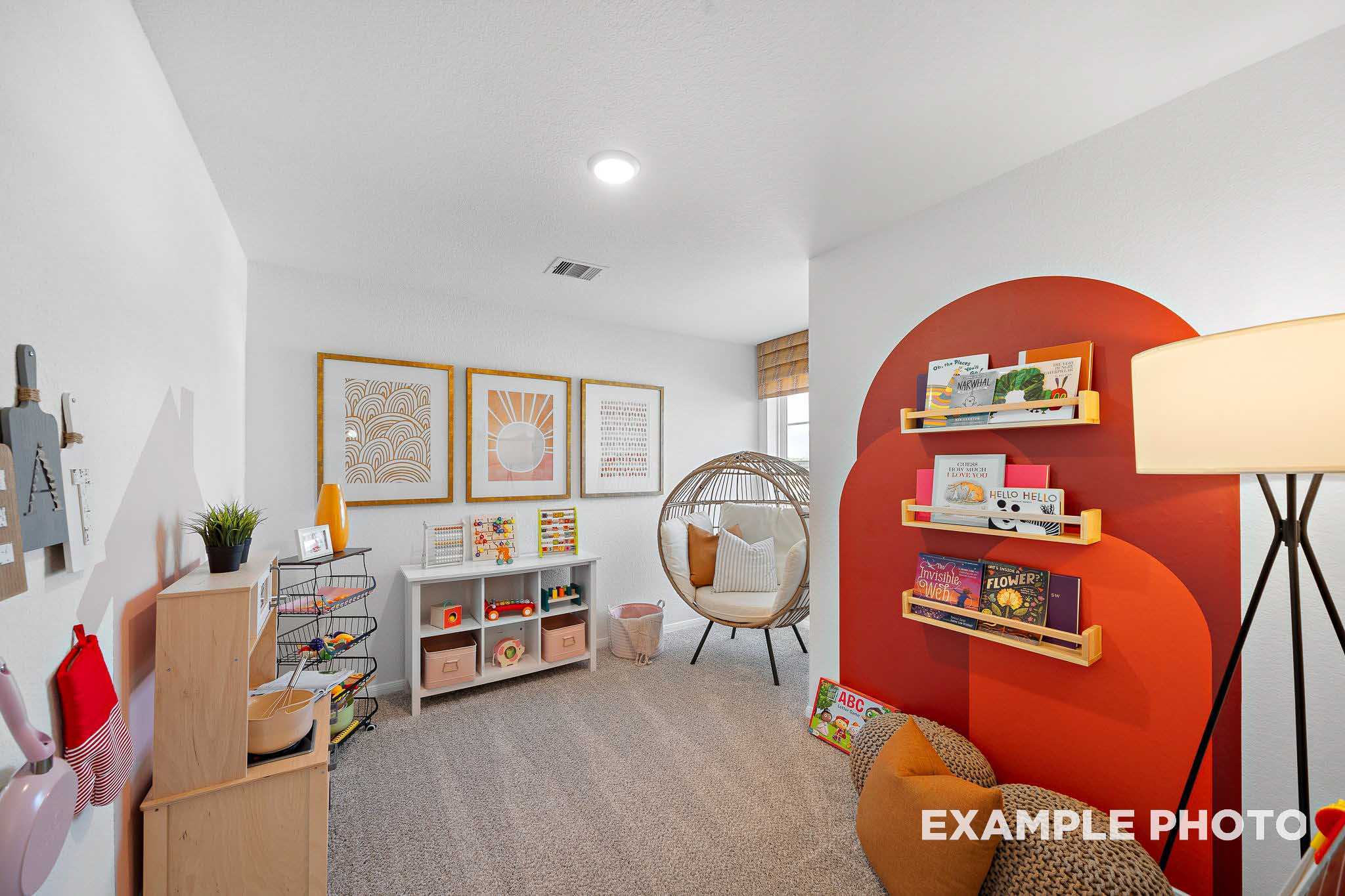Cozy children's playroom in The Sabine E home design with orange bookshelves, hanging egg chair, toys, and play kitchen