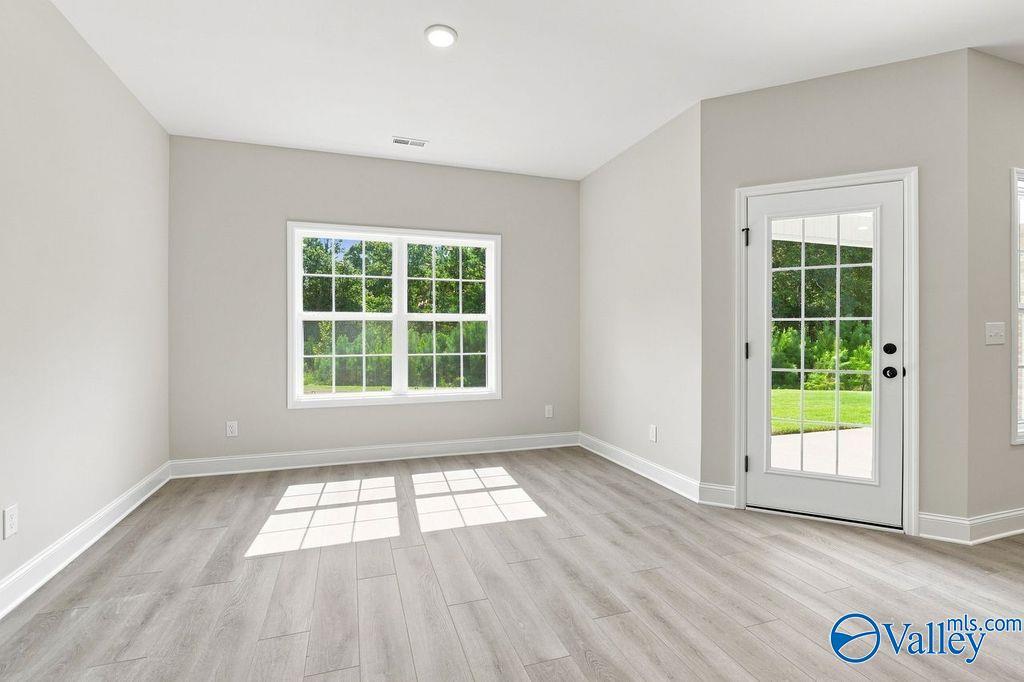 Bright empty room with luxury vinyl plank flooring, garden window, and glass-panel back door in Davidson Homes Rockford plan, Hartselle AL