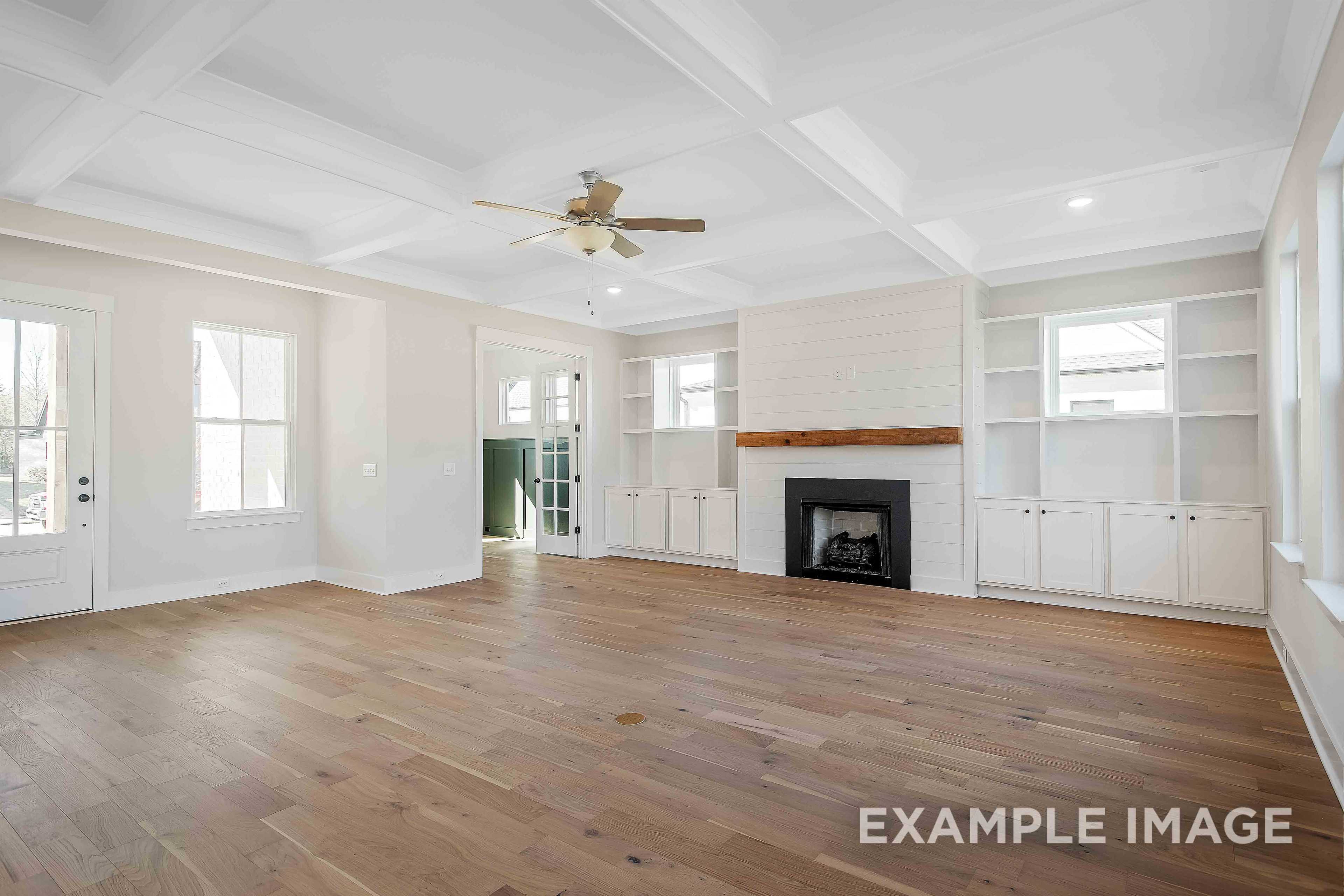 Spacious living room in The Alston A Davidson Homes featuring shiplap fireplace, built-in shelves, hardwood floors, and coffered ceiling