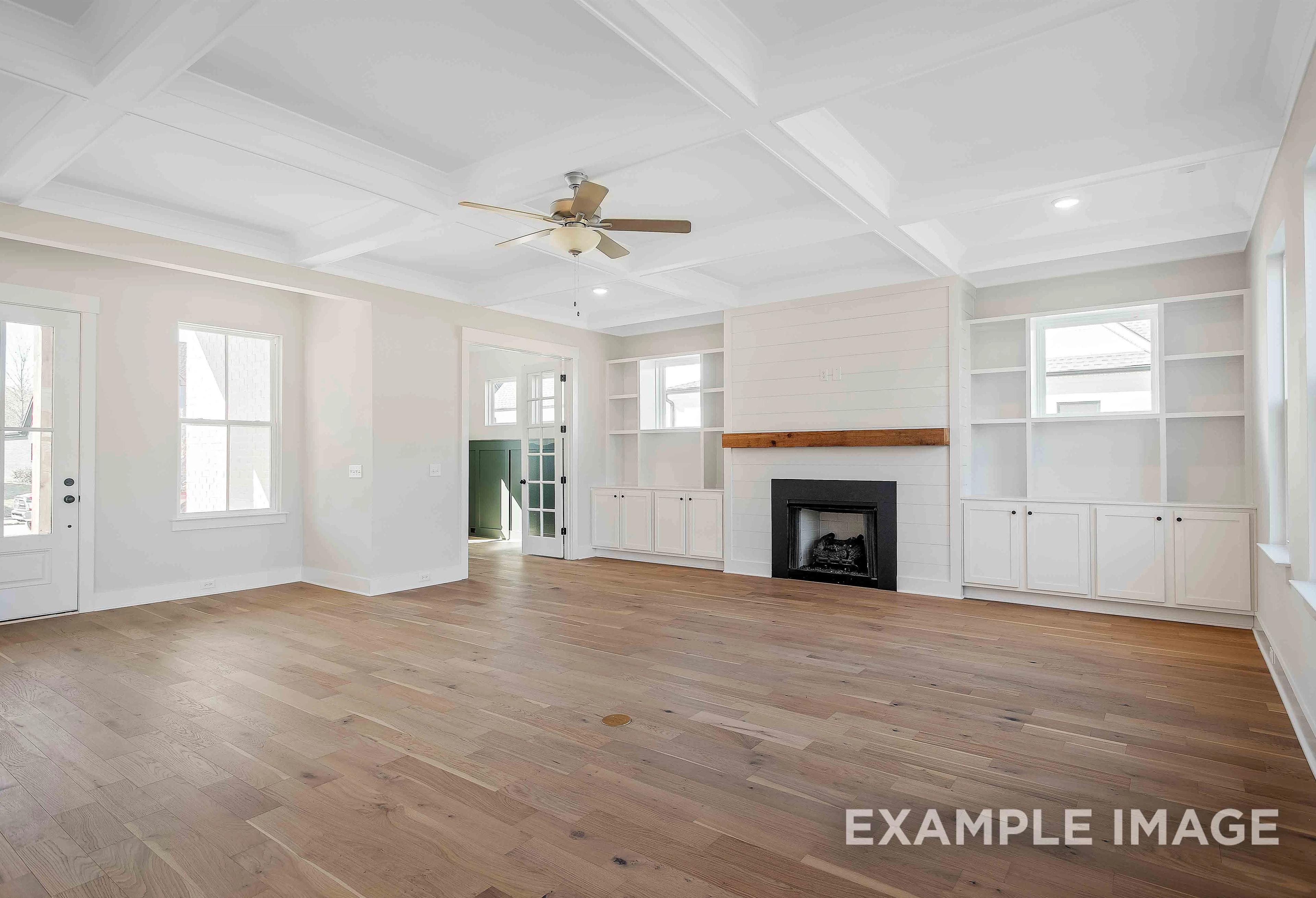 Spacious living room in The Alston A Davidson Homes featuring shiplap fireplace, built-in shelves, hardwood floors, and coffered ceiling