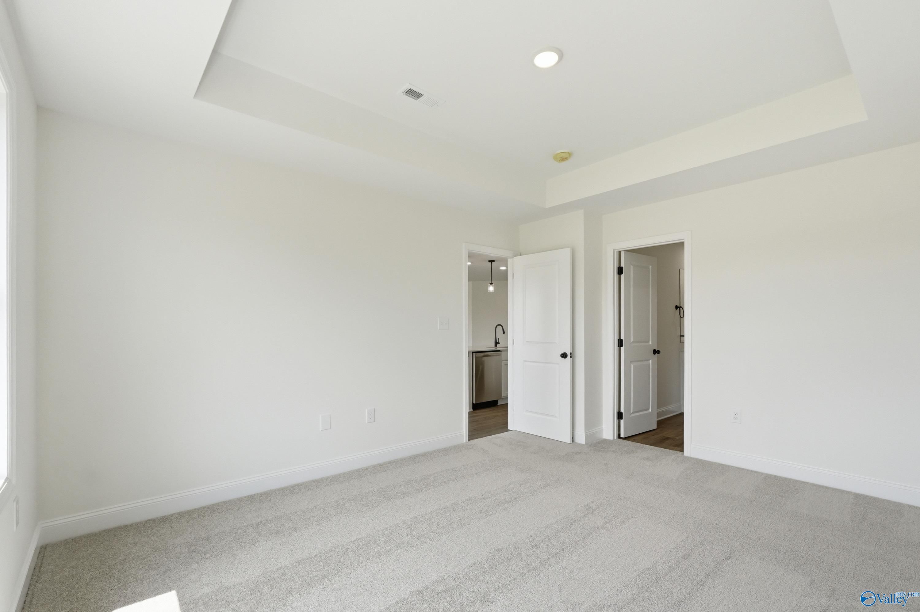 Bright bedroom with tray ceiling and plush carpet in The Franklin floor plan by Davidson Homes in New Market, Alabama.