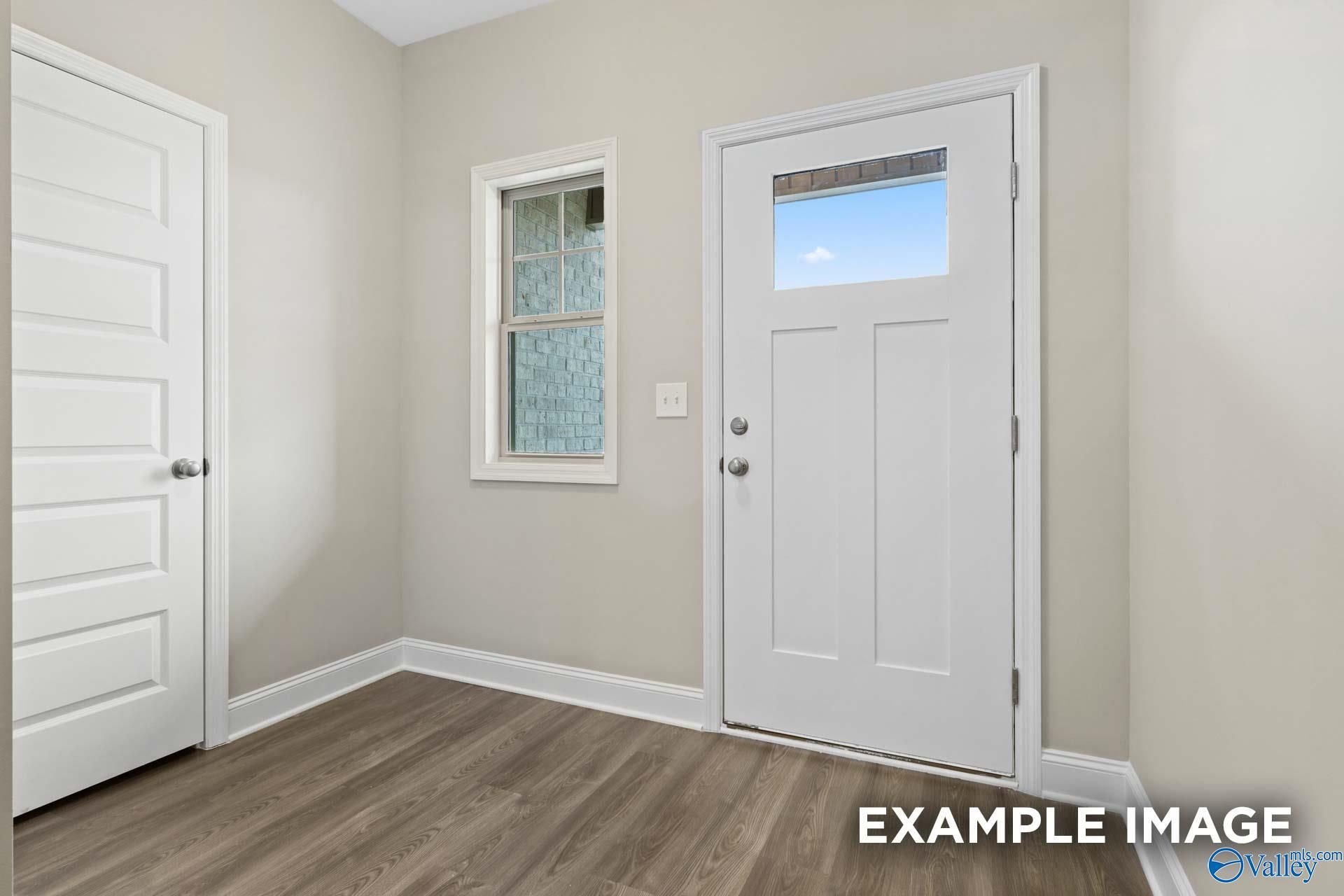 Bright entryway with beige walls, hardwood floors, and white glass-paneled door in Davidson Homes The Camilla A, Hartselle, Alabama