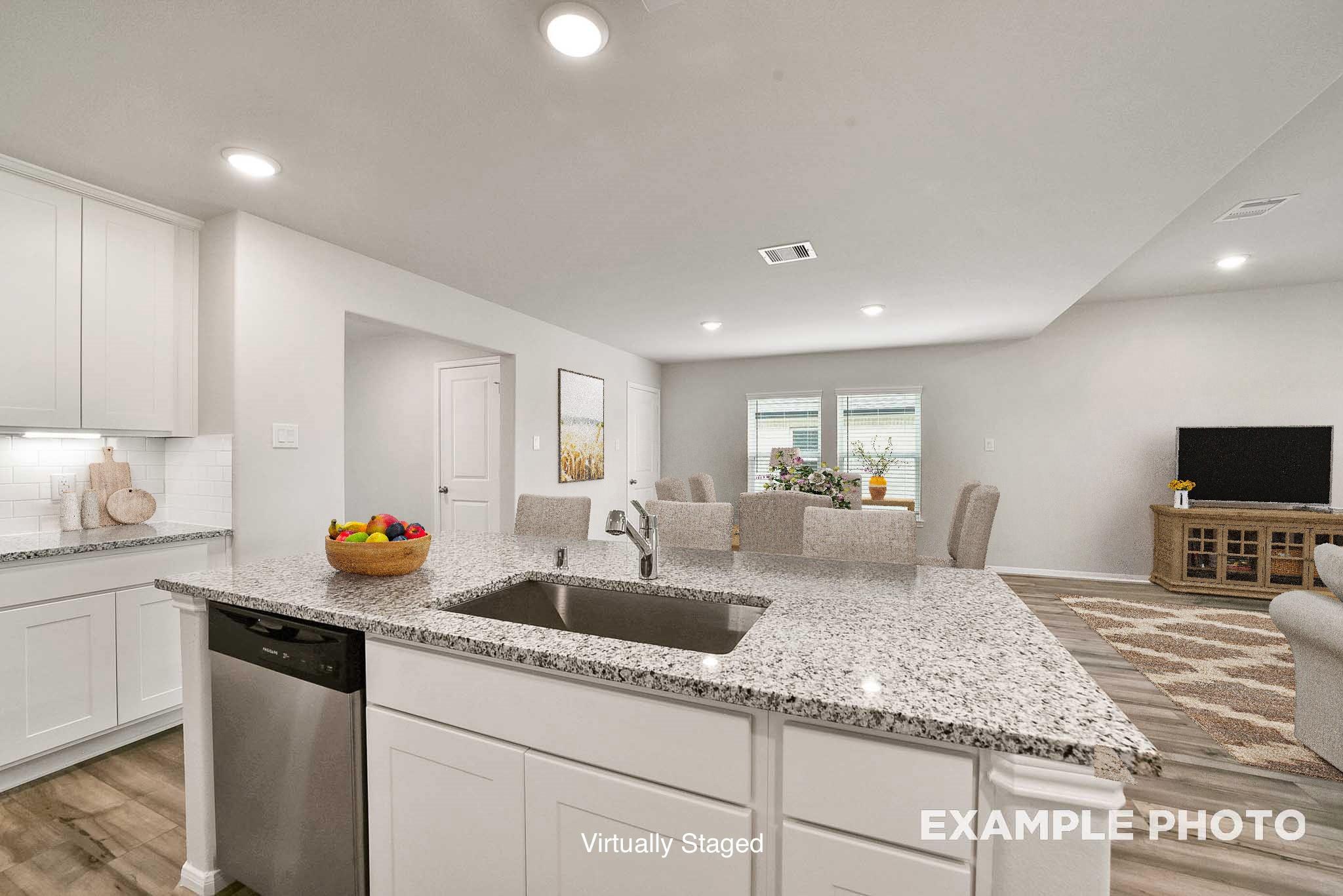 Modern open-concept kitchen with white cabinets, granite countertops, stainless sink, and dining area in Davidson Homes The Tierra B, Beasley, Texas
