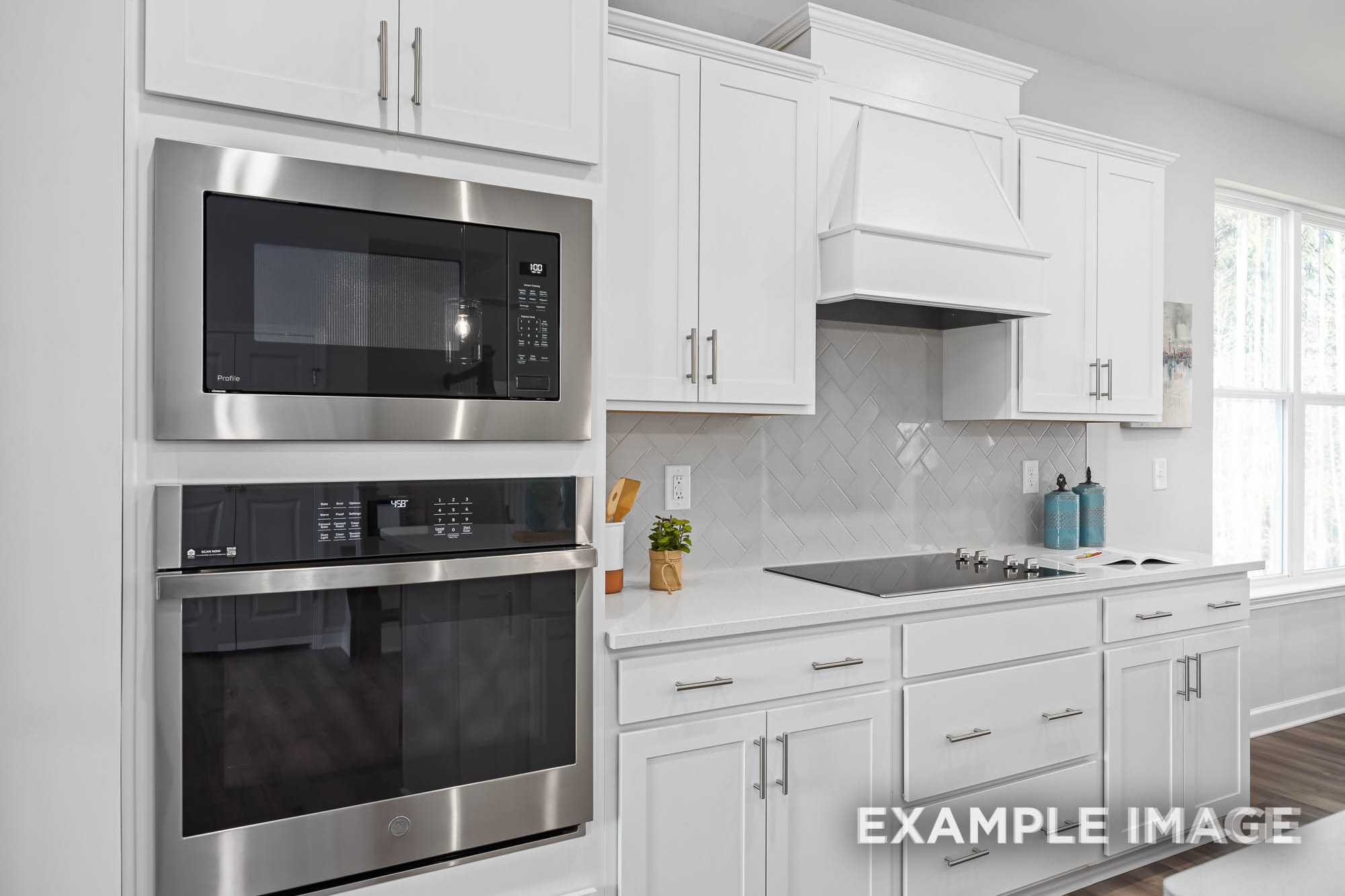 Modern kitchen in The Ash C by Davidson Homes featuring white shaker cabinets, stainless steel double oven, and subway tile backsplash