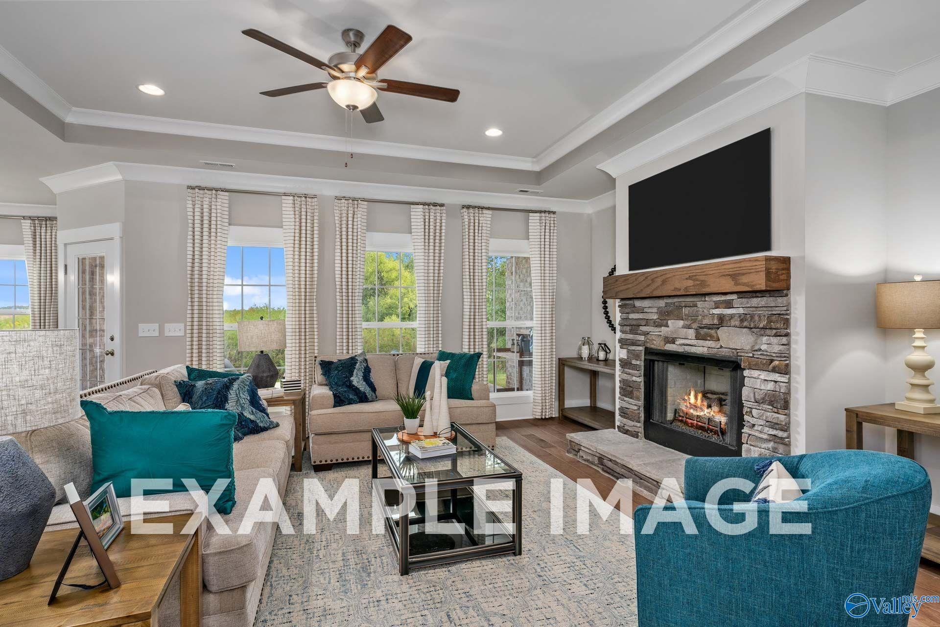 Great room with stone fireplace, tray ceiling, and large windows in Davidson Homes The Harrison floor plan, Cain Park, Hartselle, Alabama