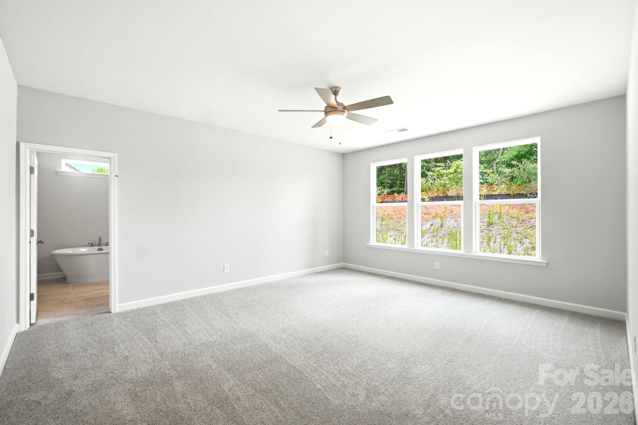 Spacious primary bedroom with carpet and en-suite bathroom in The Magnolia B floor plan at Windgate, Mooresville, NC.