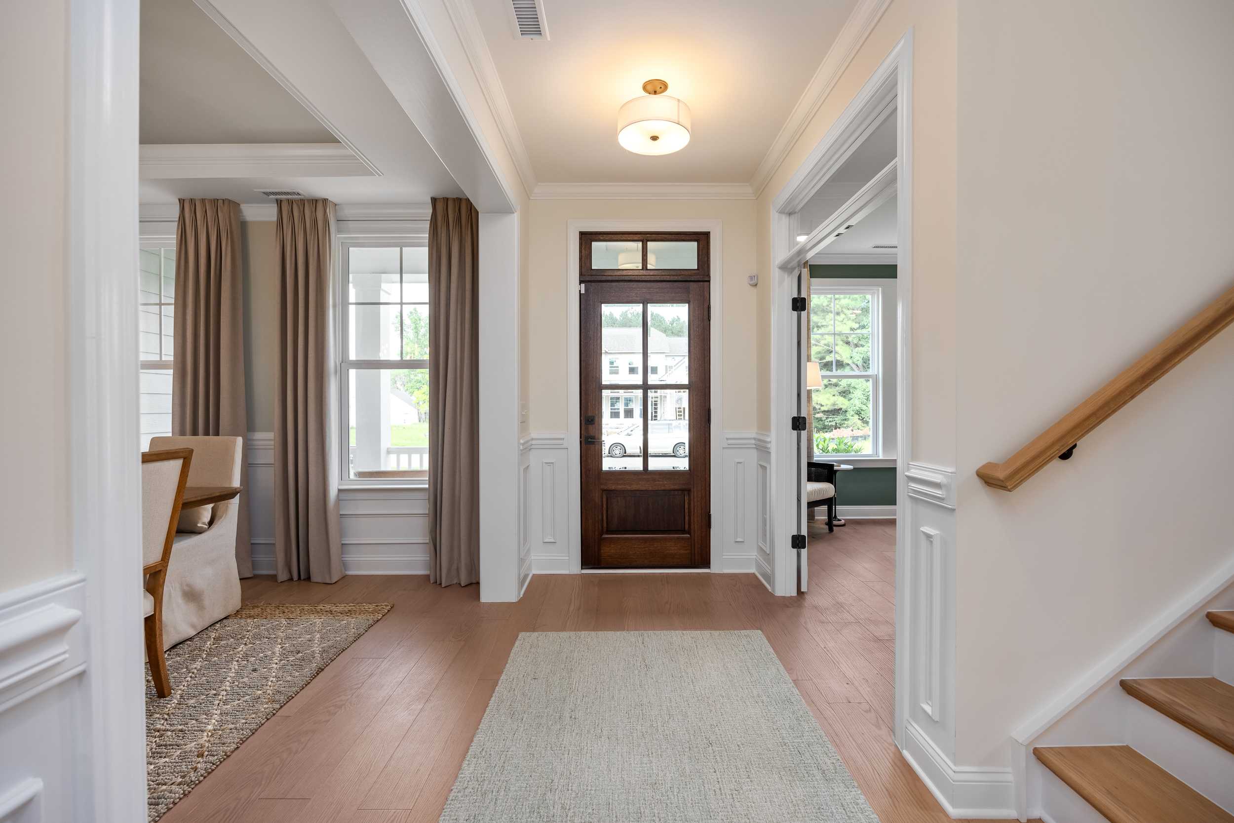Spacious foyer at Laneridge Estates in Raleigh NC with hardwood floors, wood front door, runner rug, and oak staircase