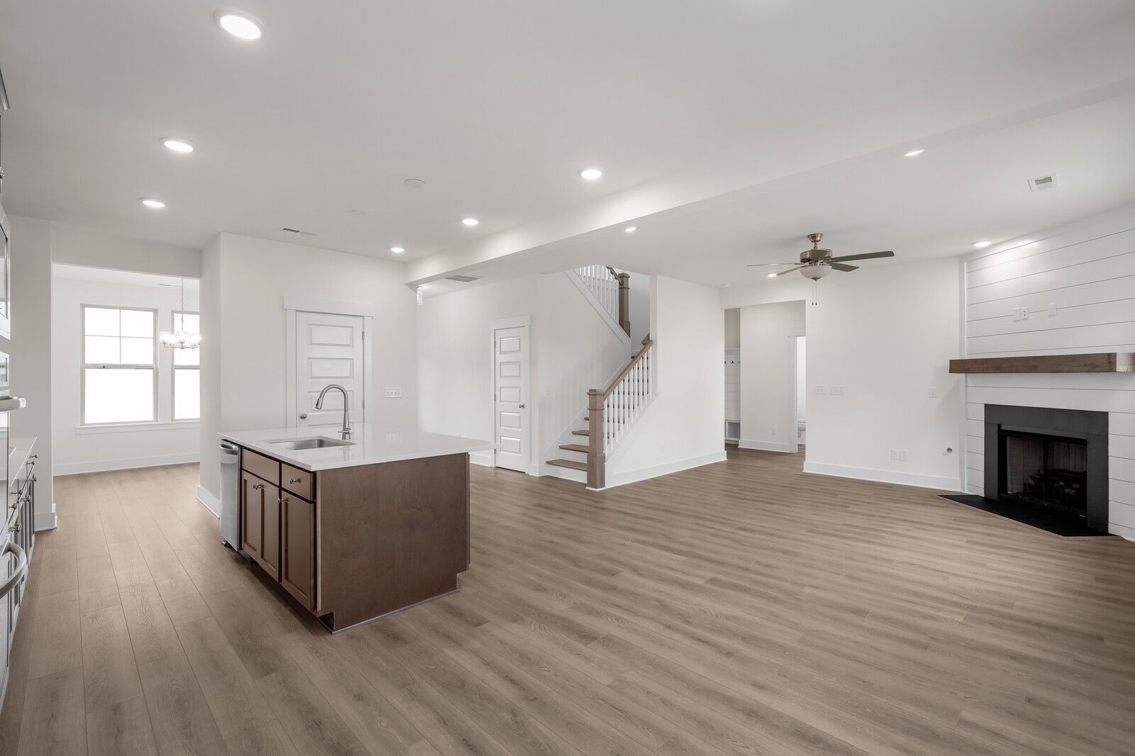 Open-concept living and kitchen with shiplap fireplace, brown island sink, hardwood floors in Davidson Homes Willow C, Gallatin, TN