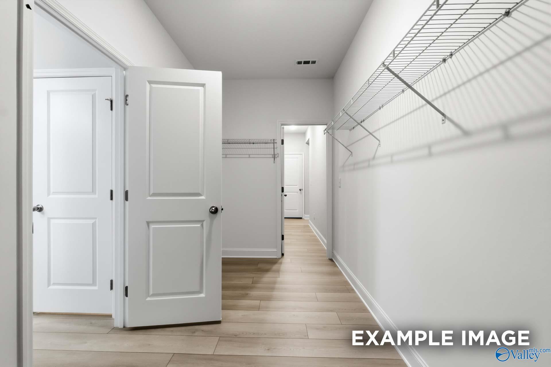 Bright hallway with open white doors to bedrooms and wire closet shelving in Davidson Homes The Harrison C, Madison Alabama
