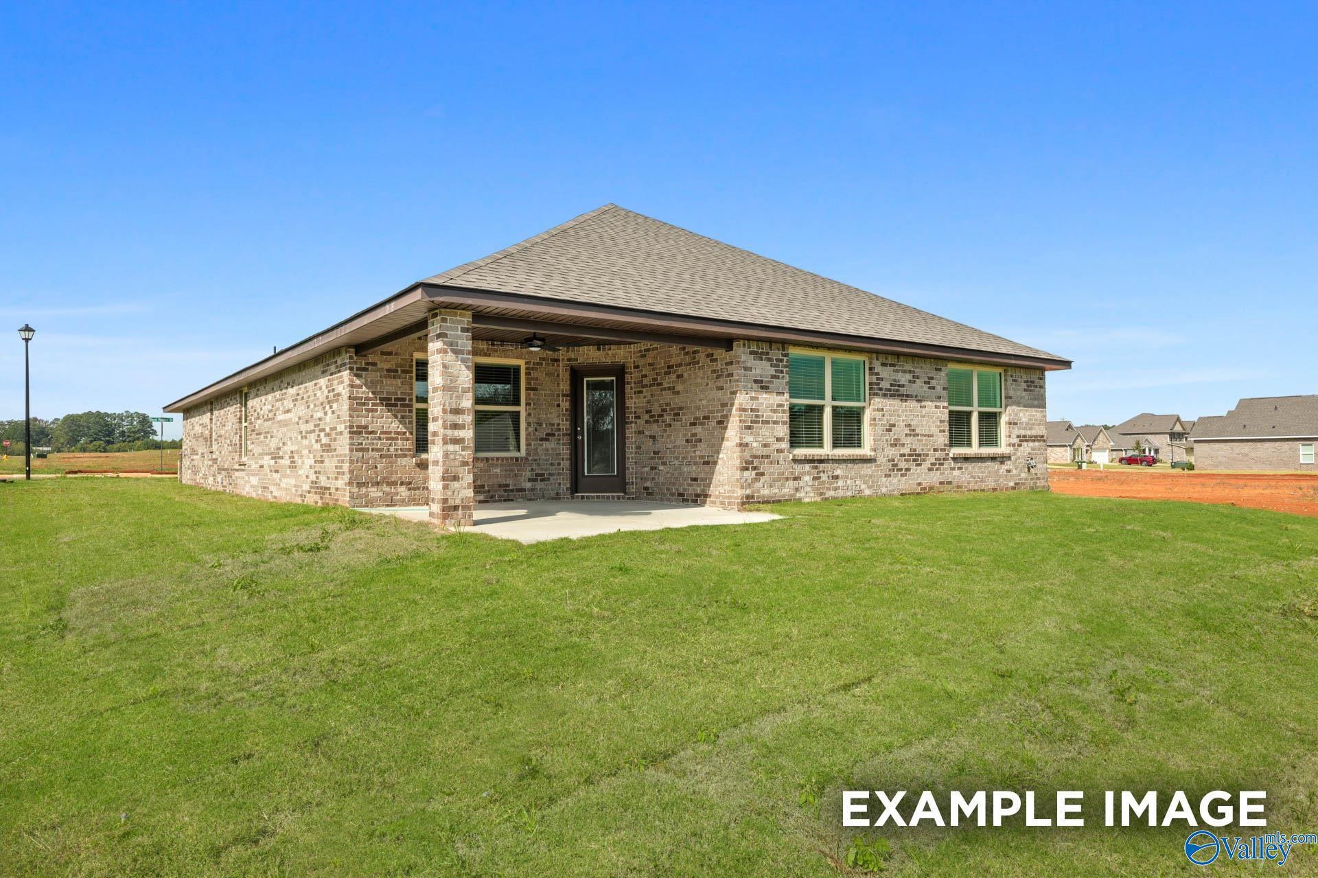 Single-story brick home with covered front porch, gabled roof, and lush green lawn in Wood Trail, Toney, Alabama - Davidson Homes Everett B