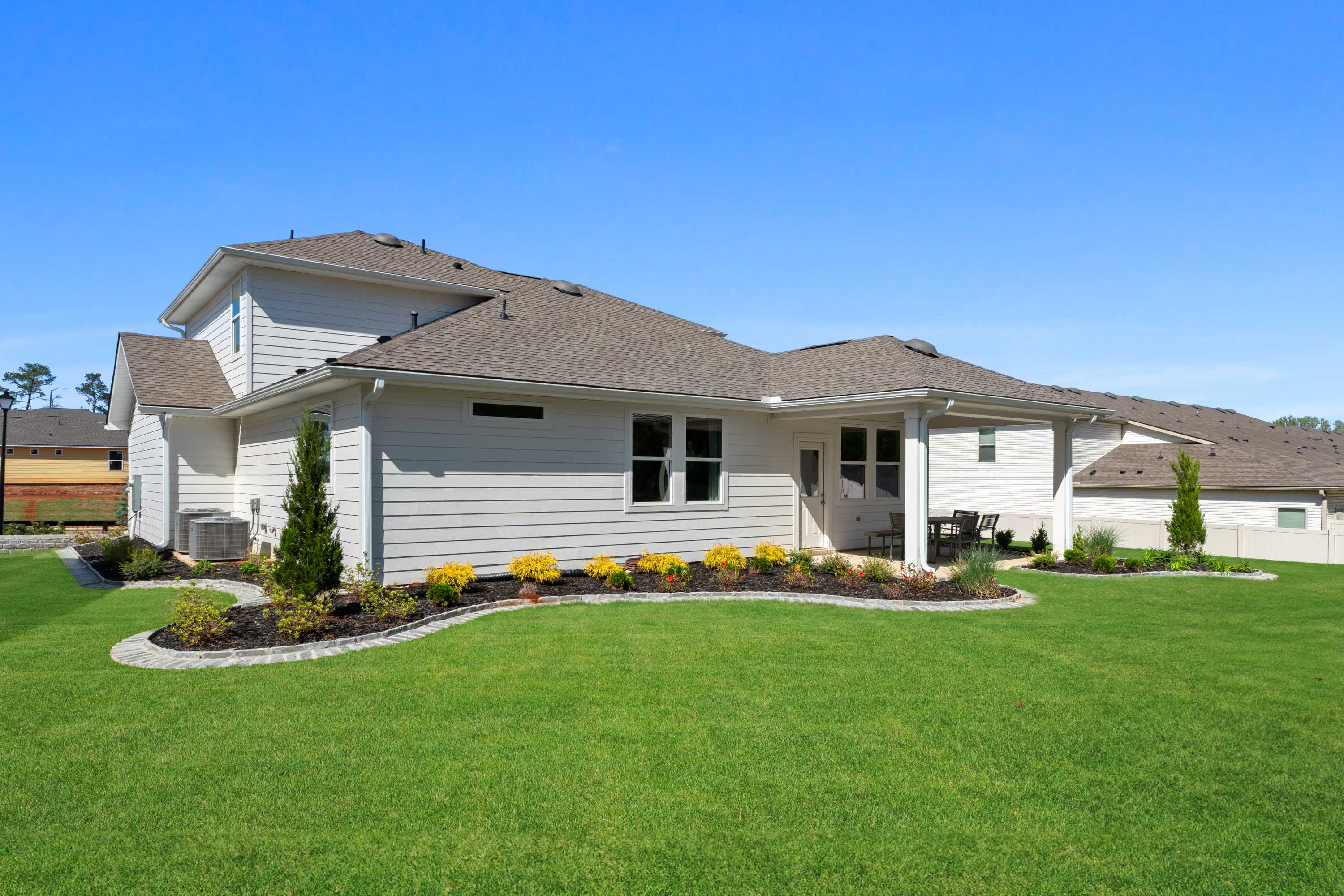 White shingled roof home exterior at Evergreen Mill in Madison, Alabama with covered side patio, outdoor seating and landscaped yard