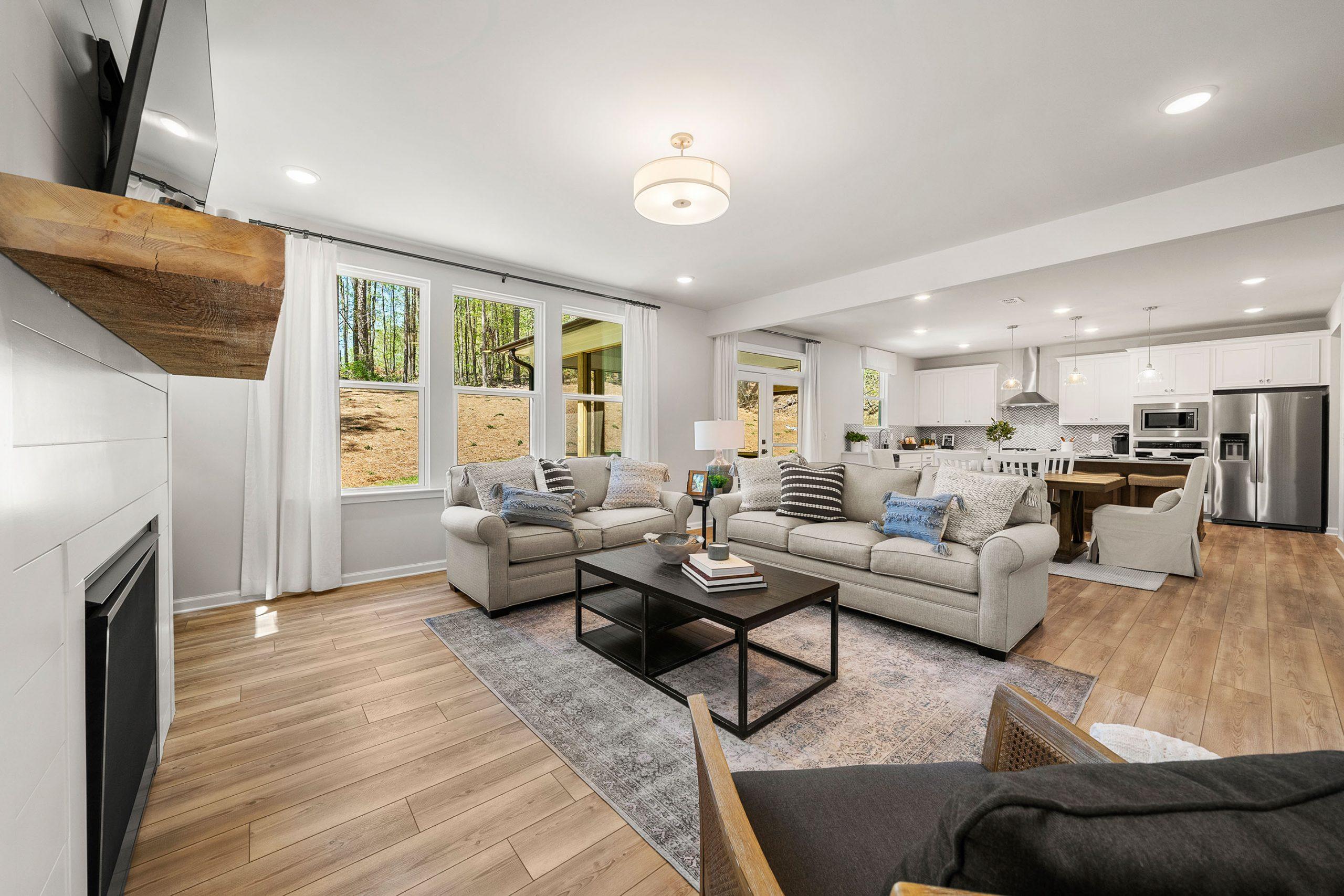 Open-concept living room and kitchen in Riverwood Dallas GA home by Davidson Homes with hardwood floors, white shiplap fireplace, and modern appliances