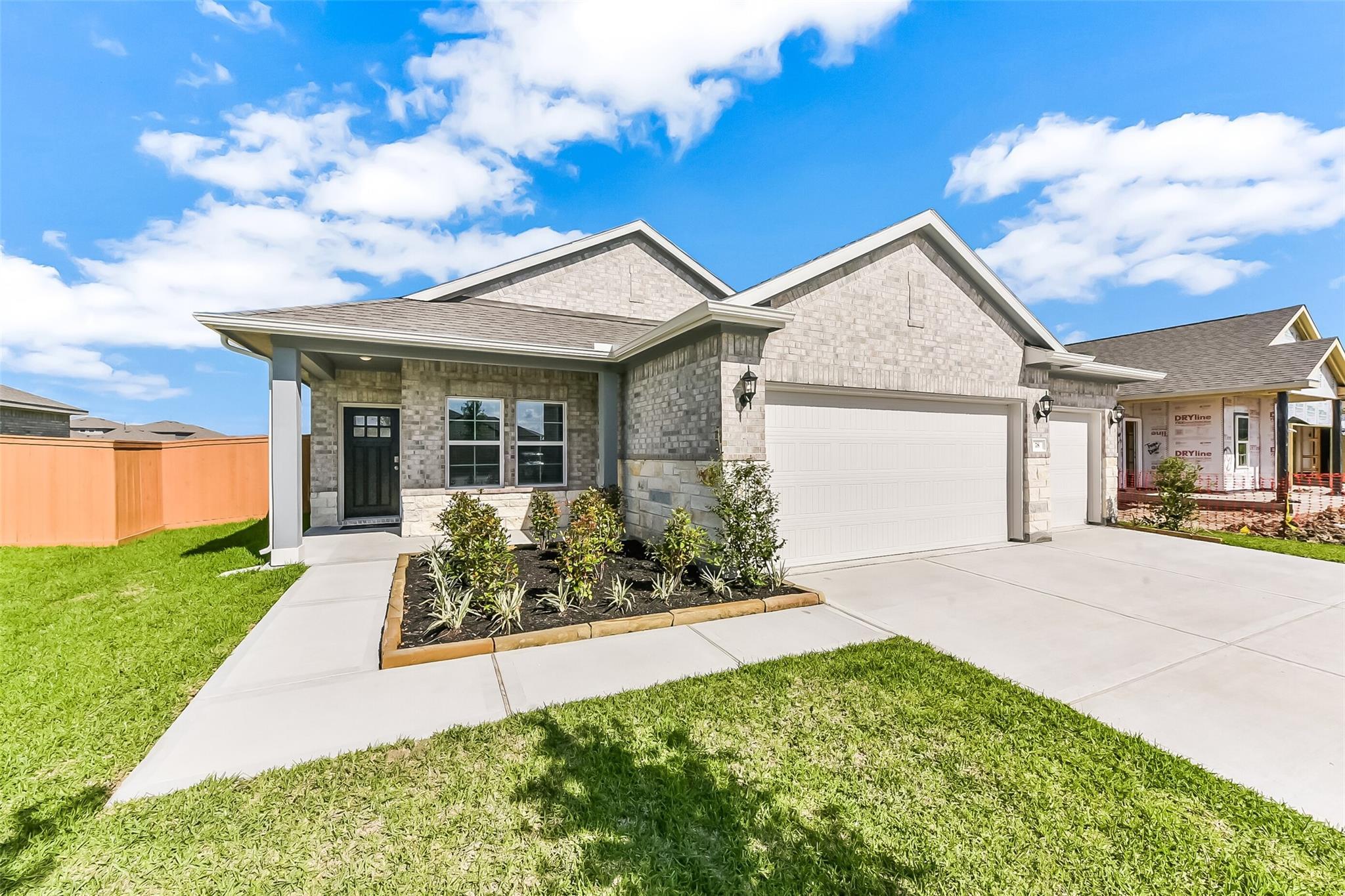 Modern brick single-story home with 3-car garage, covered porch, and landscaped yard in River Ranch Meadows, Dayton, Texas