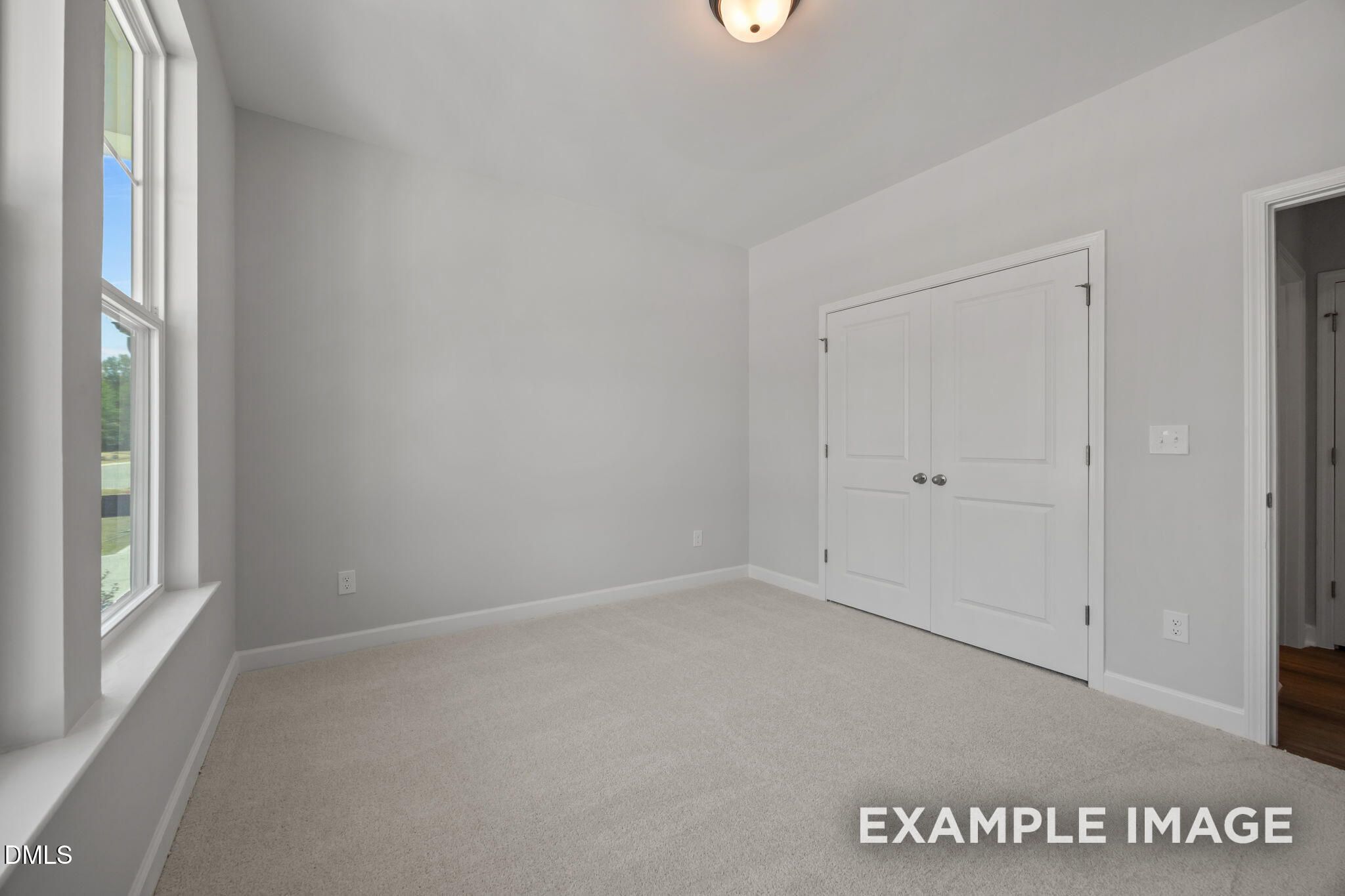 Bright bedroom with carpet, double-door closet, and large window in Davidson Homes The Beech floor plan at Wendell Ridge, NC