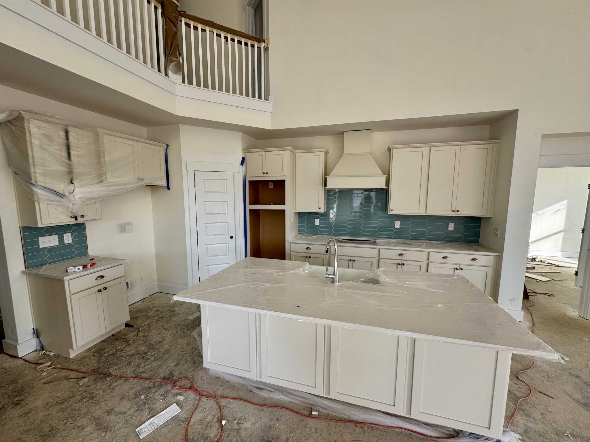 Modern white shaker kitchen with teal glass backsplash, quartz island sink, and overlooking balcony in Davidson Homes Ridgeport, Gallatin TN