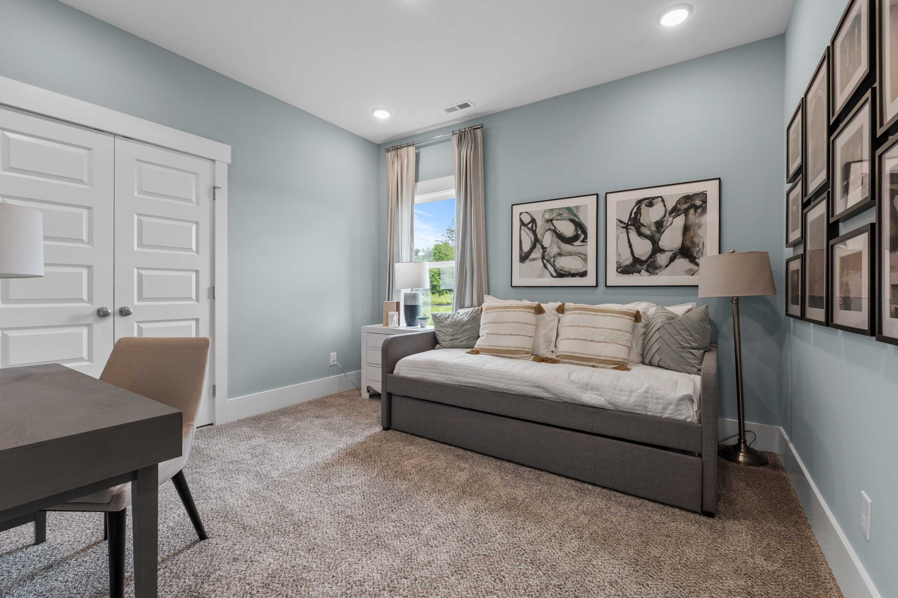 Serene blue home office at The Highlands in Arab Alabama with desk, trundle bed, abstract art, and window view