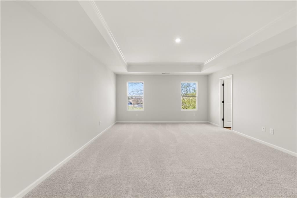 Spacious empty upstairs bedroom with large windows, carpeted floor in Davidson Homes Cary A, Winder, Georgia