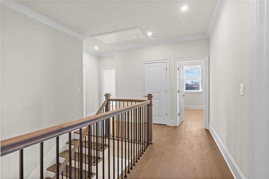 Upstairs hallway featuring wooden staircase, beige walls, and hardwood floors in Davidson Homes The Arlington A, East Cobb, Georgia