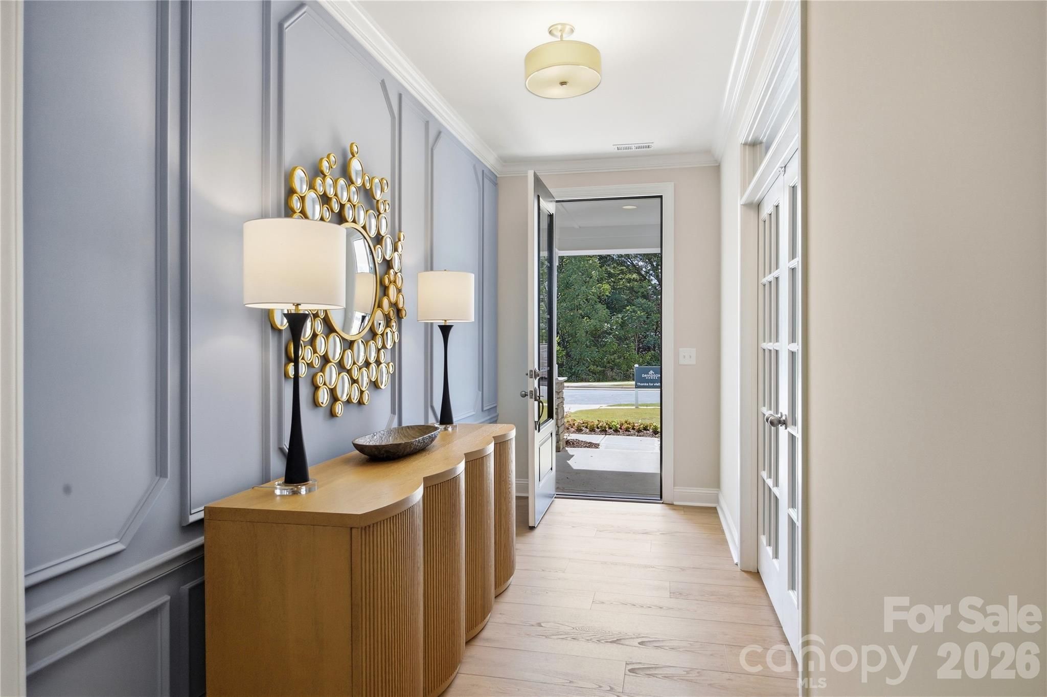Elegant foyer with wainscoting, gold mirror, and console table in Davidson Homes The Hickory C II, Enclave at Belmont, North Carolina