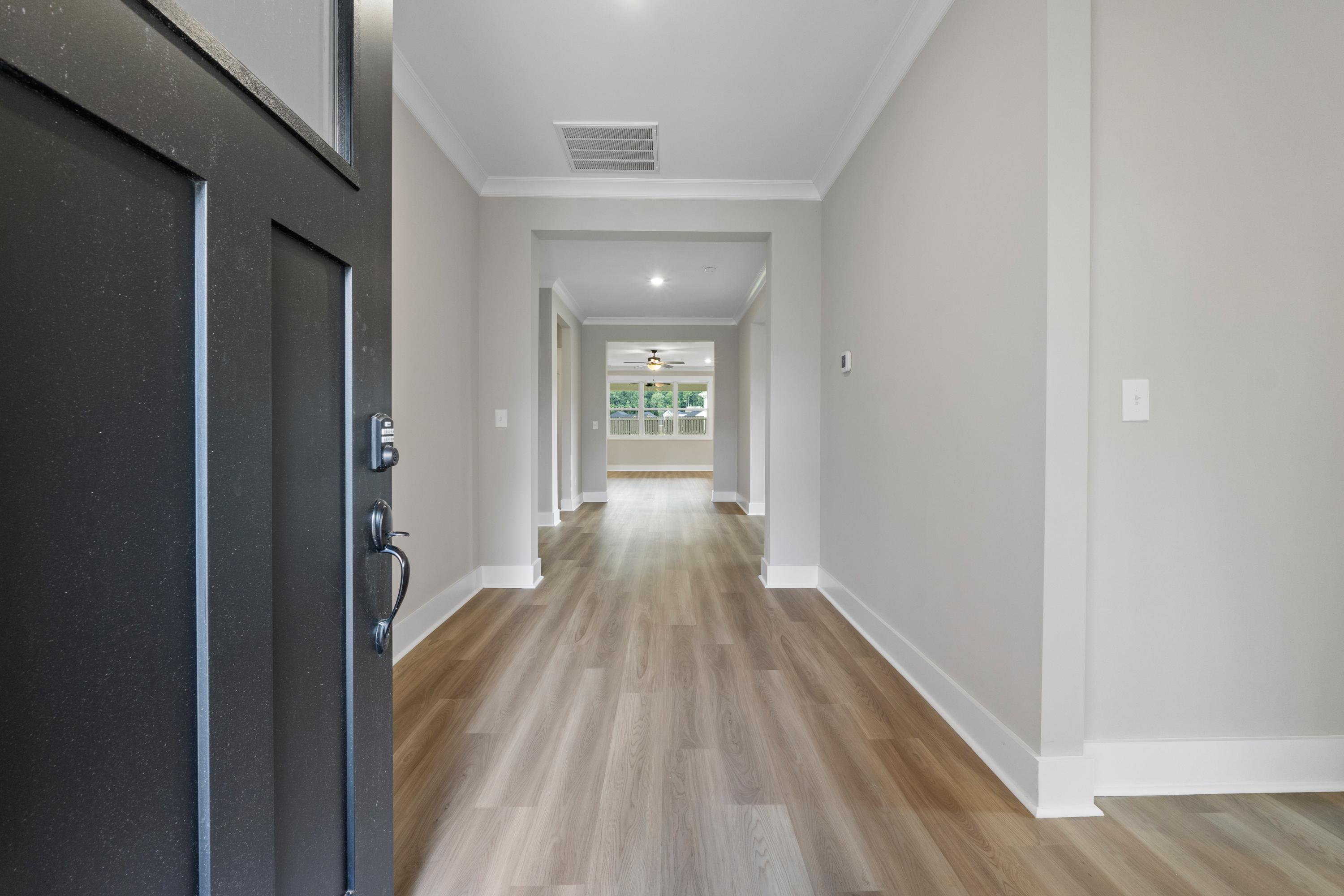 Spacious entry hallway in The Oxford B home featuring open black door, light wood floors, and neutral gray walls