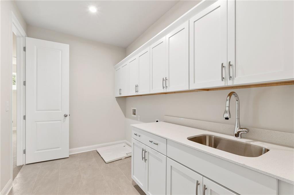 Modern laundry room with white shaker cabinets, utility sink, and washer-dryer space in Davidson Homes The Hampton C, Buford, Georgia