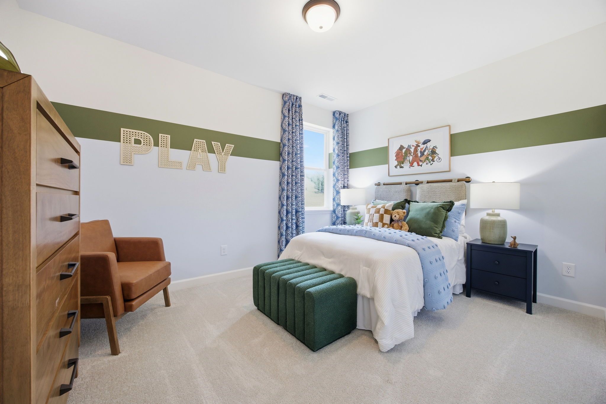 Cozy secondary bedroom in The Ashport featuring green accent wall, playful decor, and comfortable bedding.