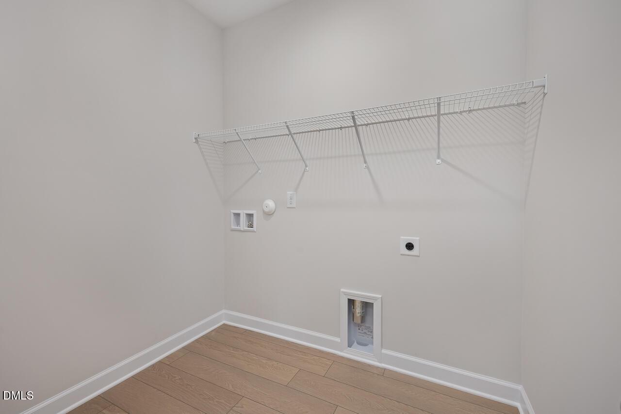 Spacious laundry room with wire shelving, outlets, and floor utility in The Daphne D by Davidson Homes, Lillington, NC