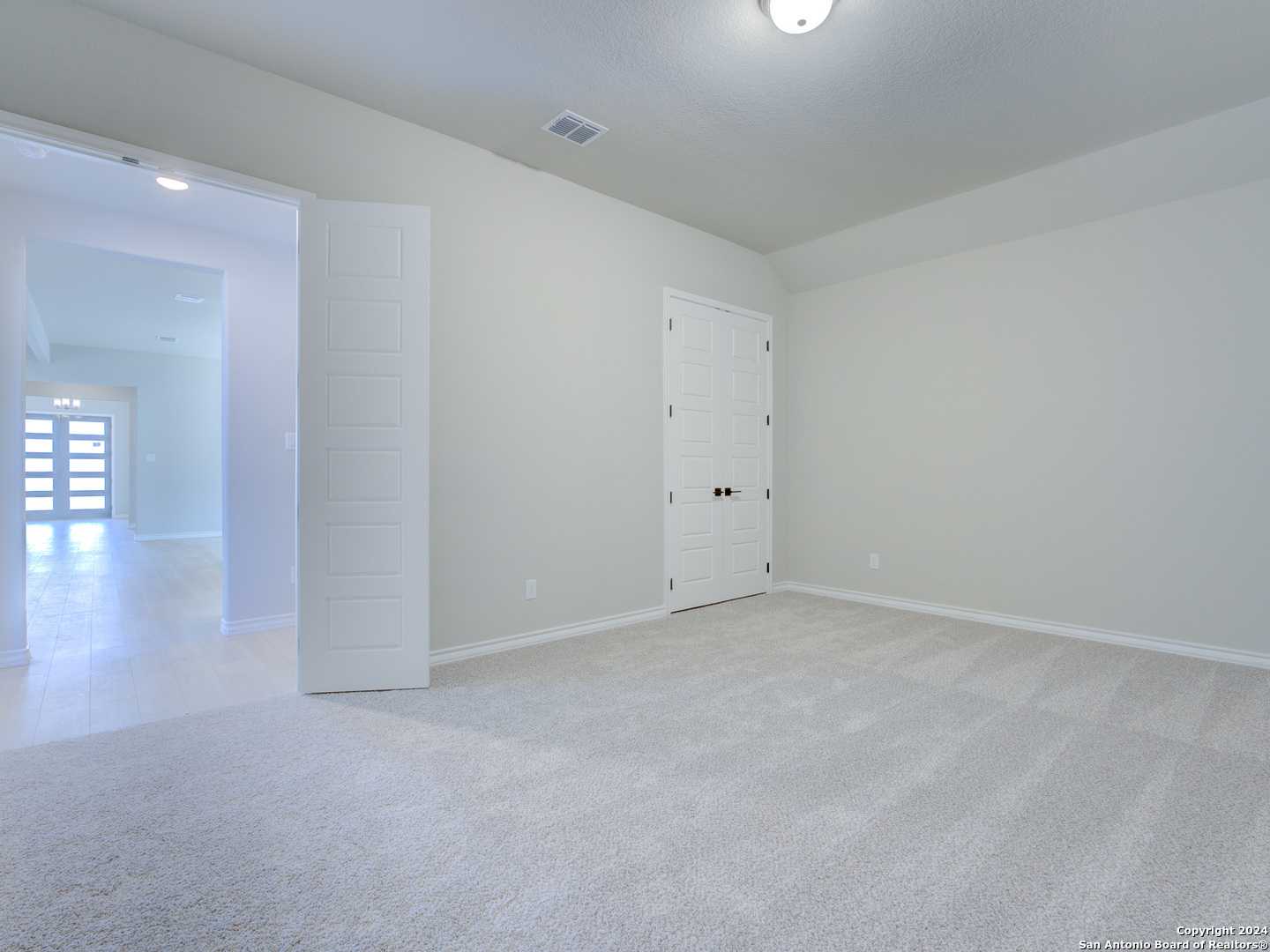 Empty carpeted study with closet doors and open entry to foyer in Davidson Homes The Summerlin A, Castroville, Texas