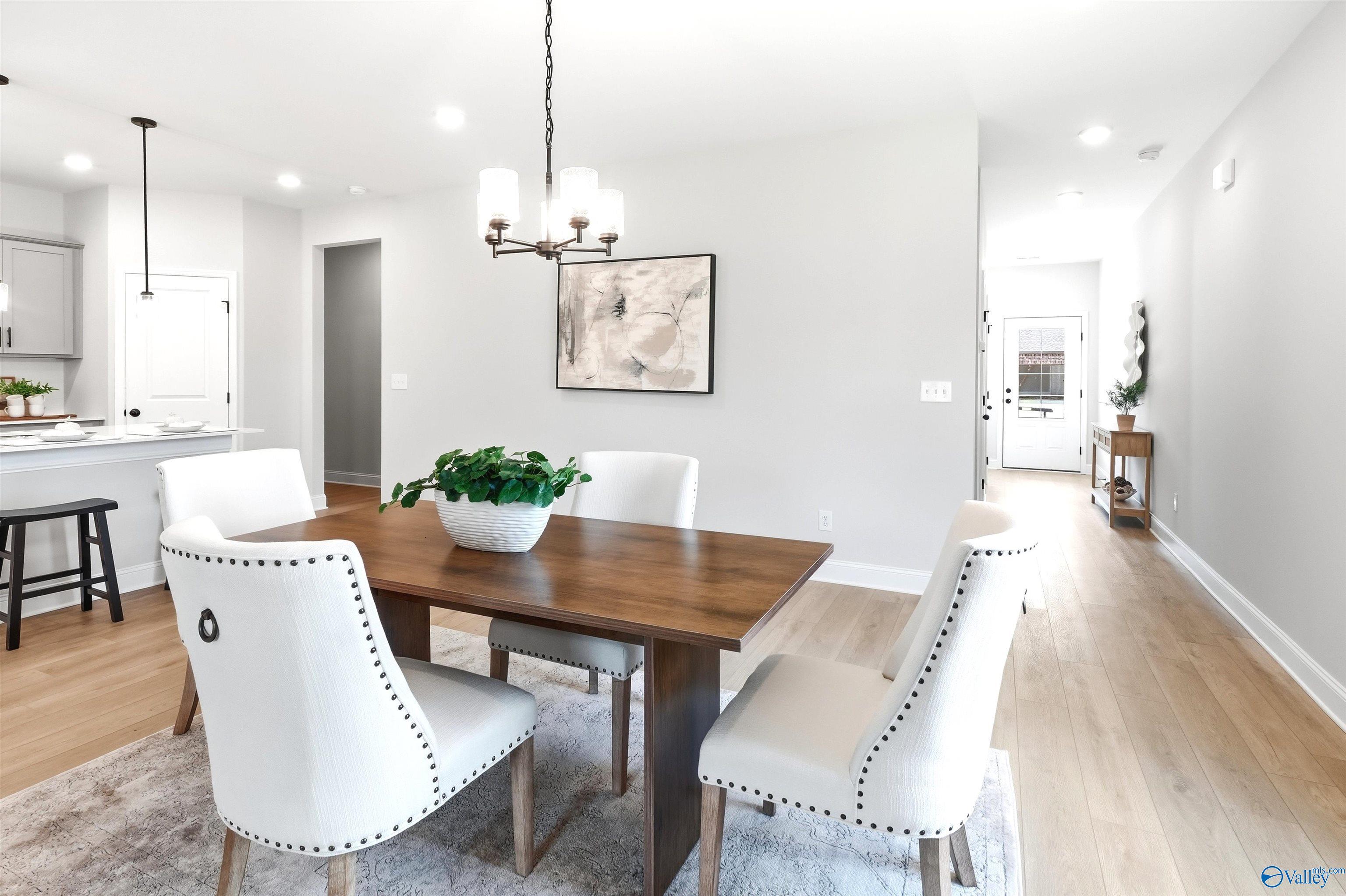 Bright dining area with wood table, white nailhead chairs, and chandelier in Davidson Homes The Russell A, Huntsville, AL