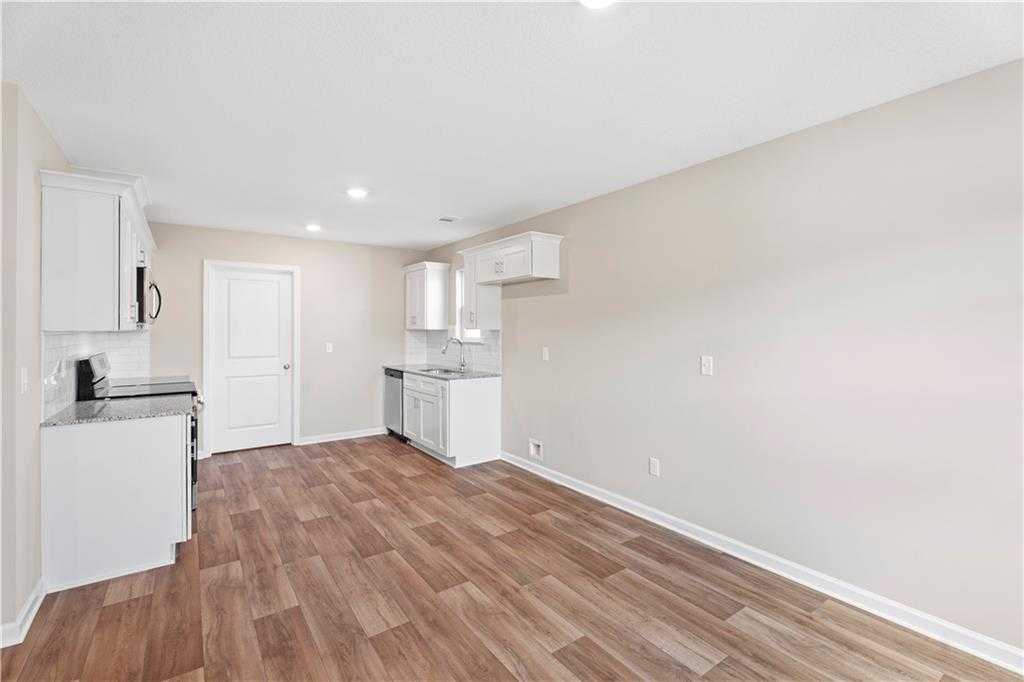 Modern kitchen featuring white cabinets, stainless sink, and hardwood-look floors in Davidson Homes The Washington, Phenix City, Alabama