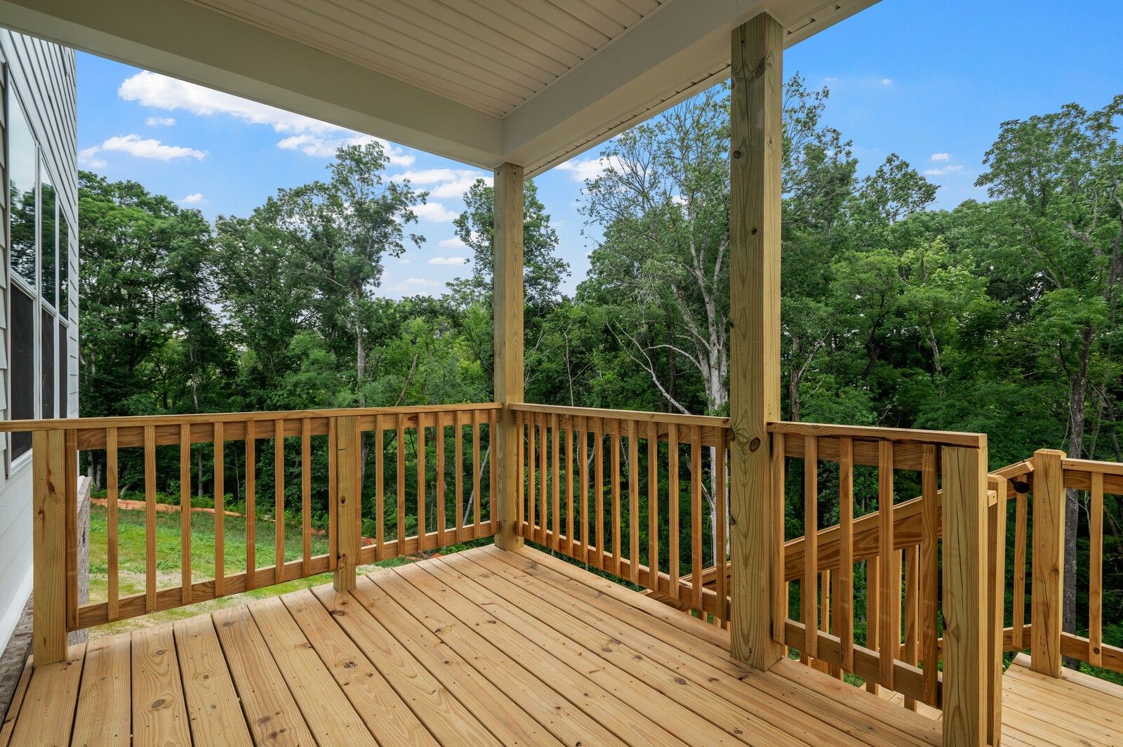 Covered wooden deck overlooking lush woods at The Logan C floor plan home in Calista Farms, White House, Tennessee.