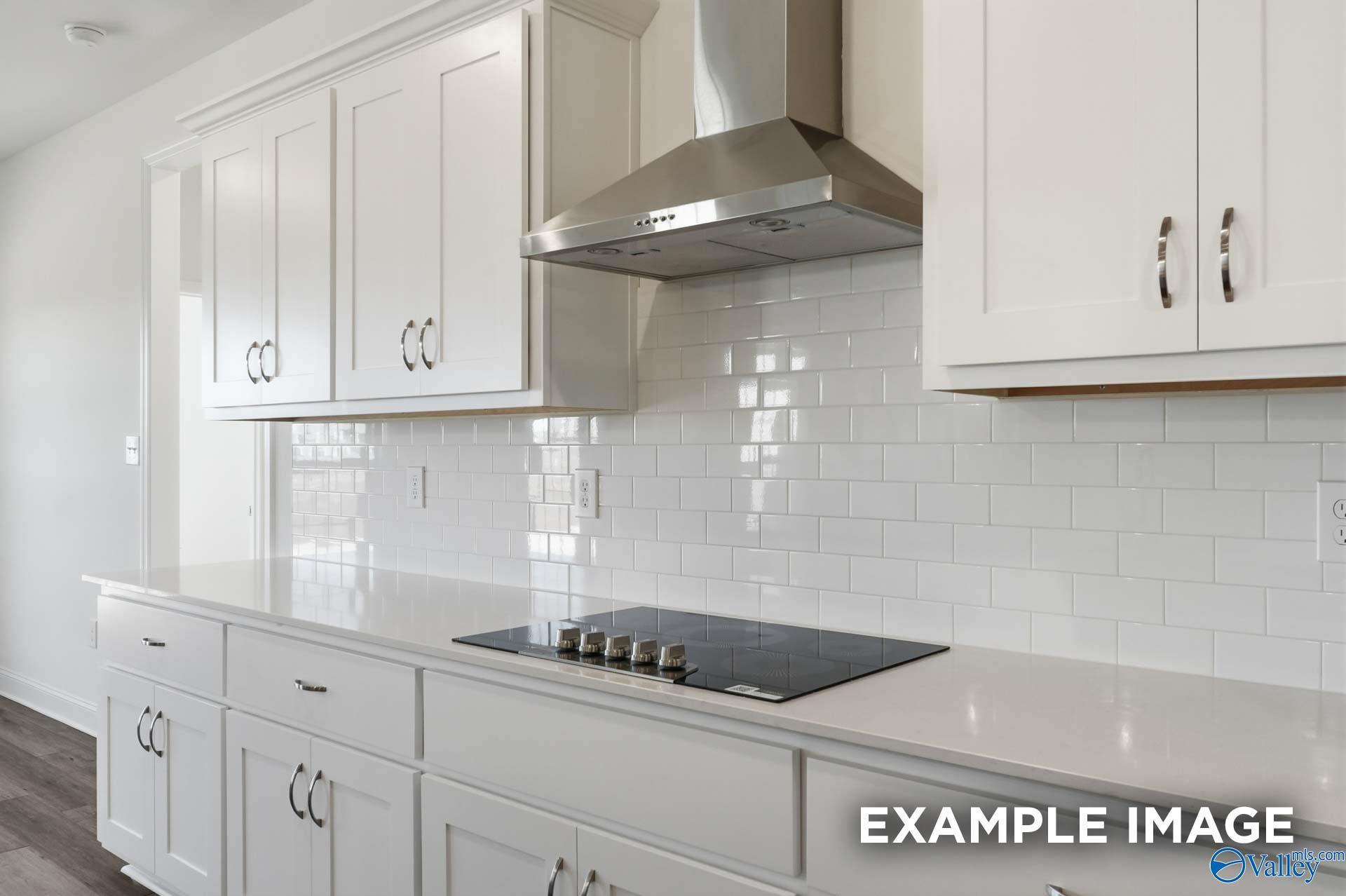Modern kitchen with white shaker cabinets, subway tile backsplash, and stainless vent hood in Briercreek, Meridianville home.