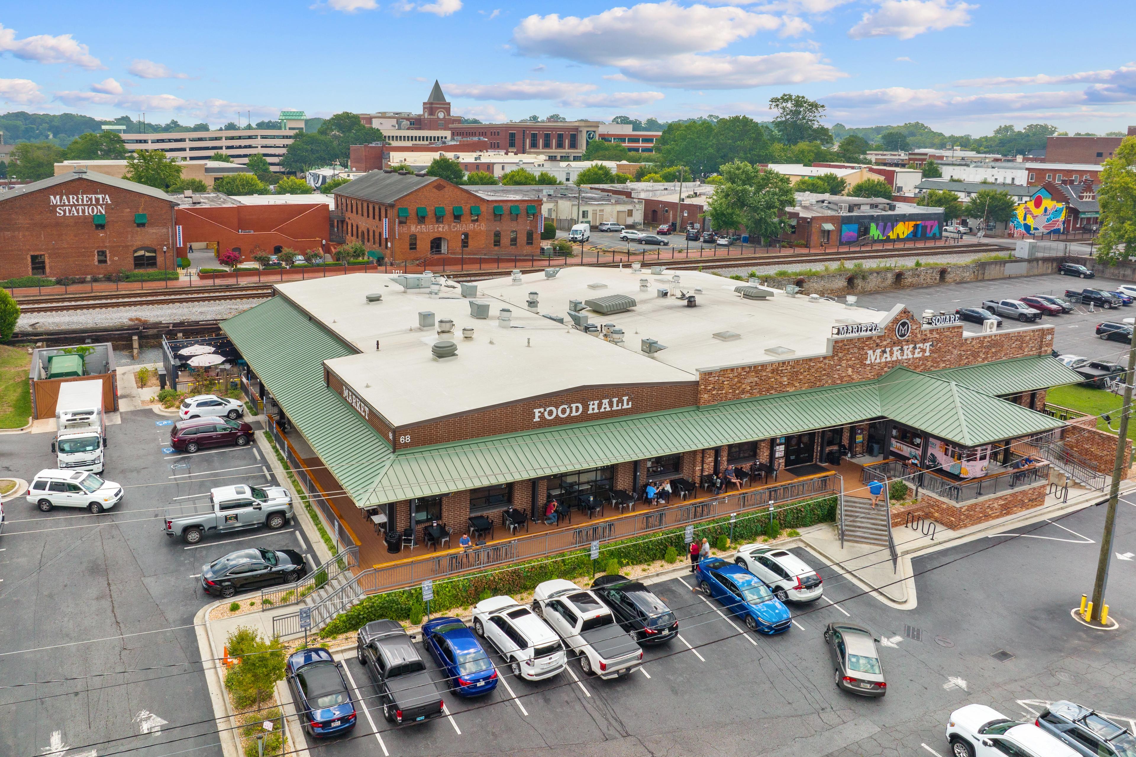 Aerial view of Marietta Food Hall and Market with green awning, brick warehouses, outdoor seating, and parking near Rosehill Townhomes