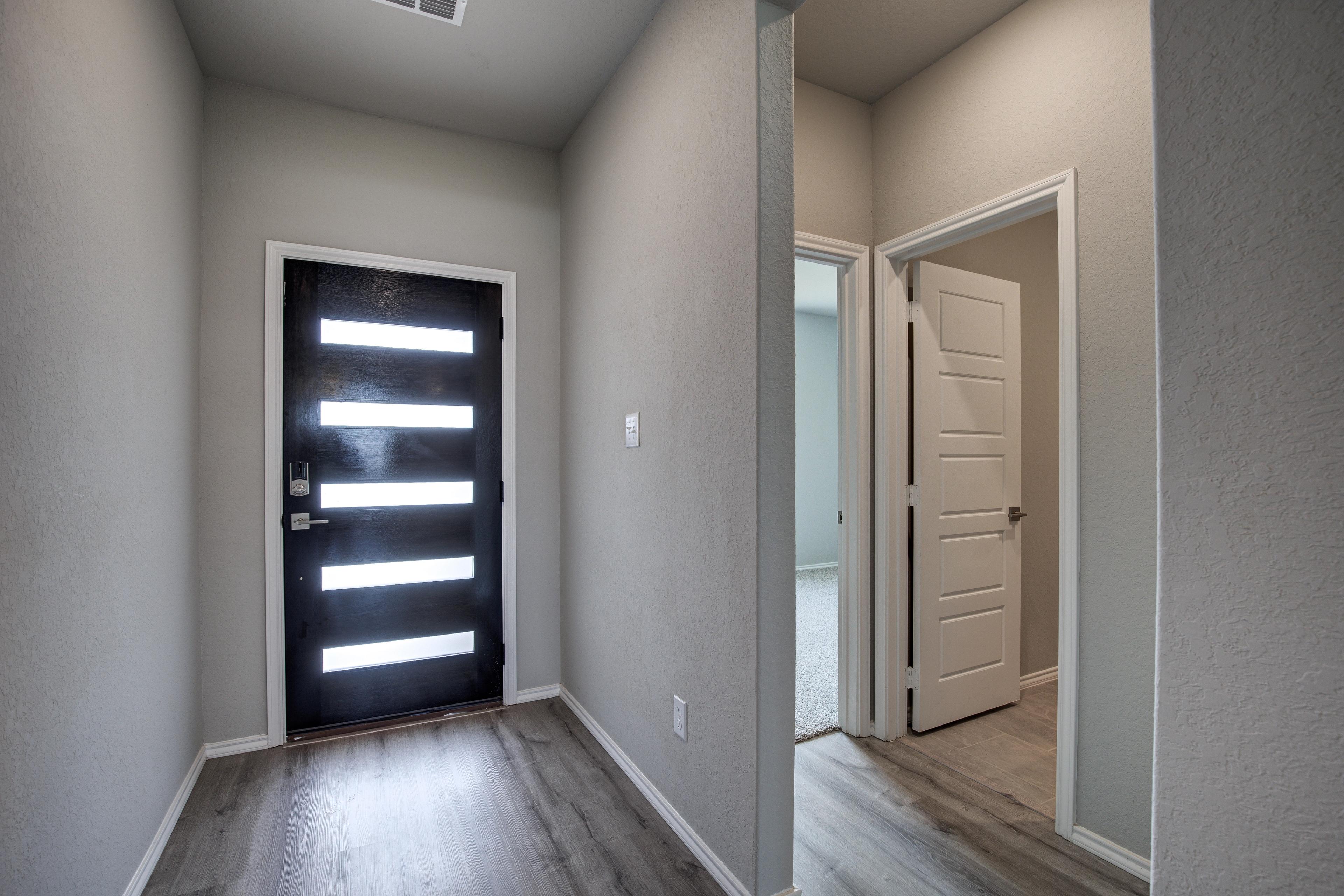 Modern entryway in The Asheville home design featuring sleek black front door with frosted glass panels and neutral beige walls