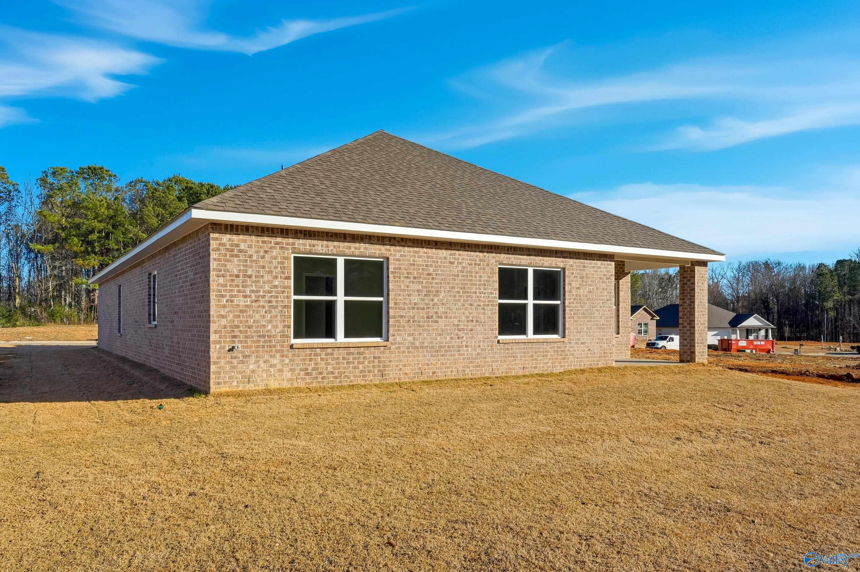 Single-story brick home exterior with gabled roof, large windows, and covered porch in The Highlands, Arab, Alabama