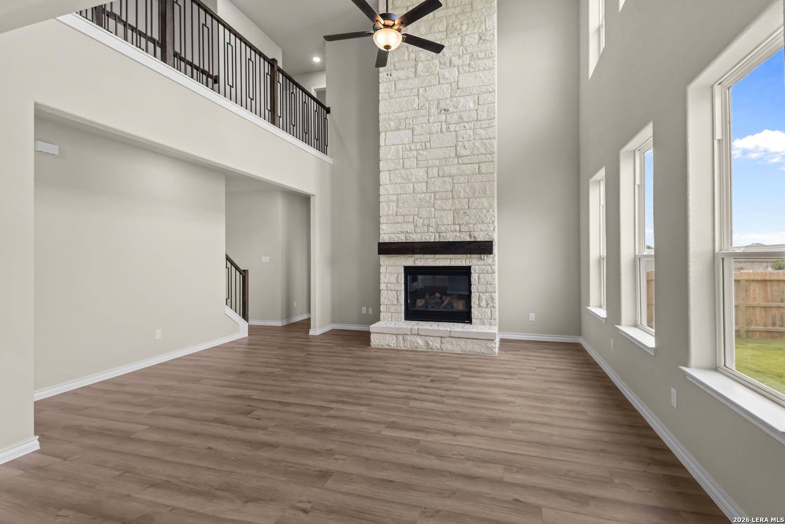 Two-story living room with a floor-to-ceiling stone fireplace in The Danbury H by Davidson Homes, Castroville, Texas.