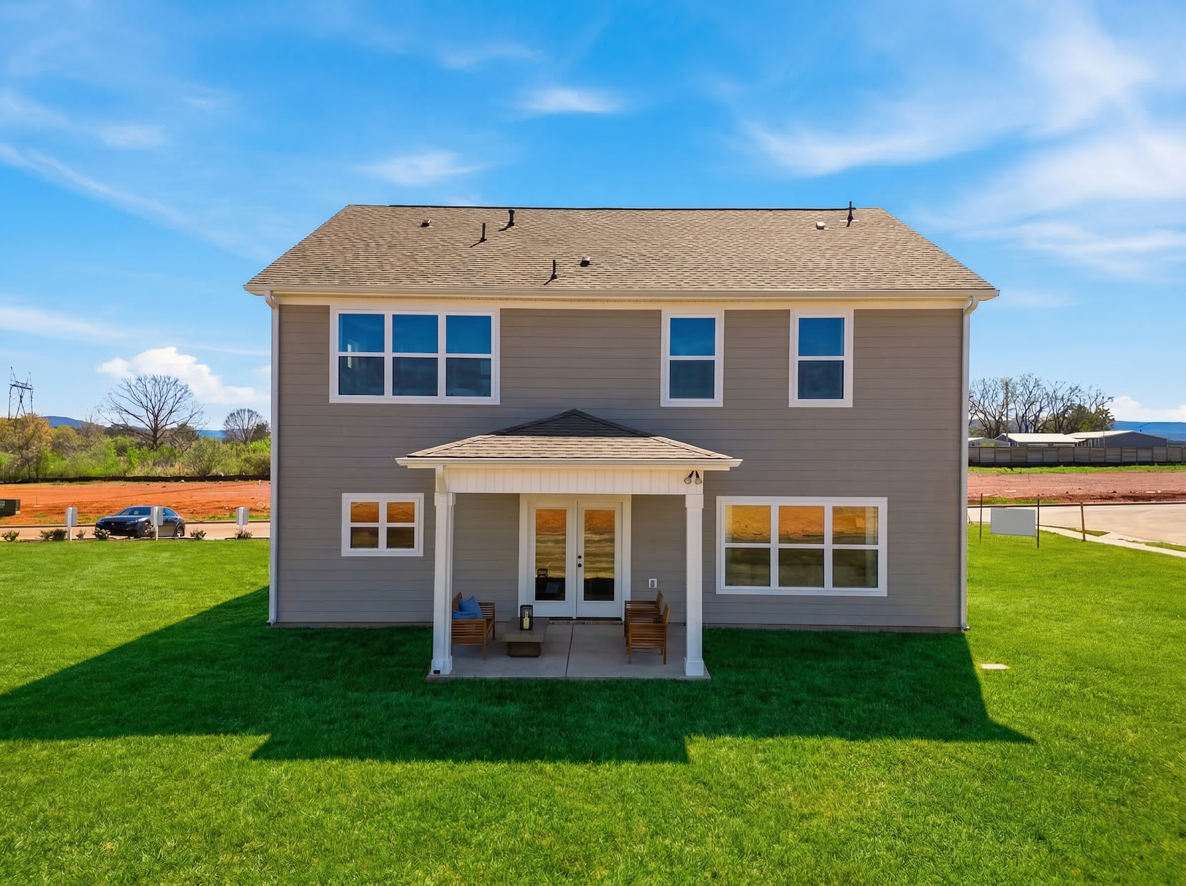 Back exterior of modern two-story home at Berry Cove in New Market, Alabama with covered porch, double doors, and green lawn