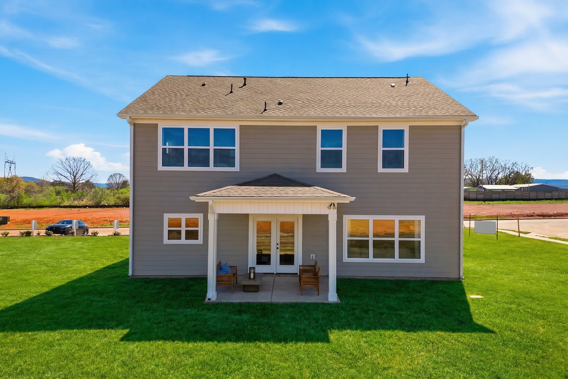 Back exterior of modern two-story home at Berry Cove in New Market, Alabama with covered porch, double doors, and green lawn