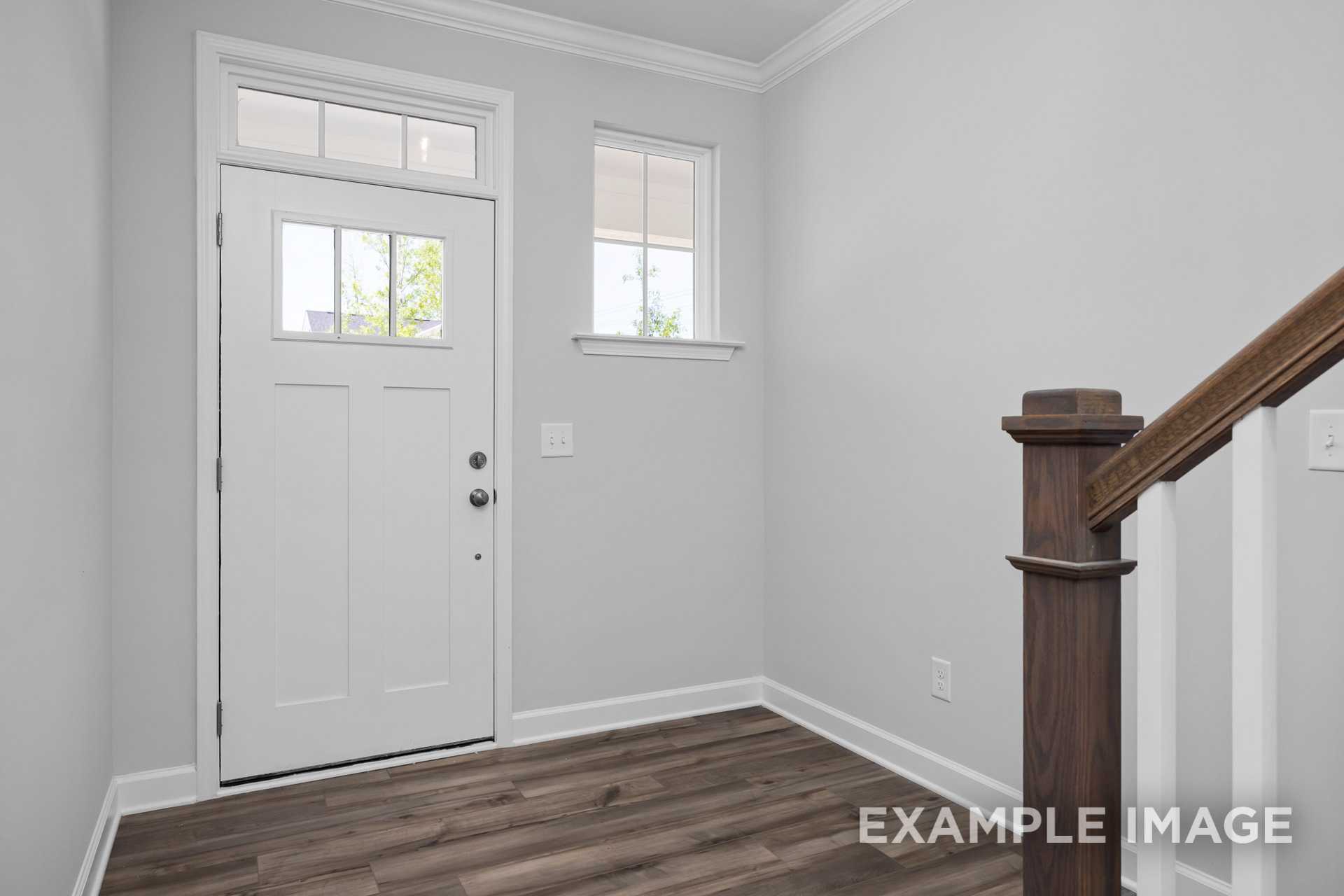 Spacious entry foyer in The Preston B with white glass-paneled door, sidelight window, gray walls, hardwood floors, and wooden staircase